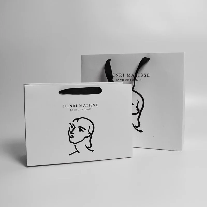 White laminated gift bag with black printed artwork and ribbon handles, ideal for luxury retail packaging.