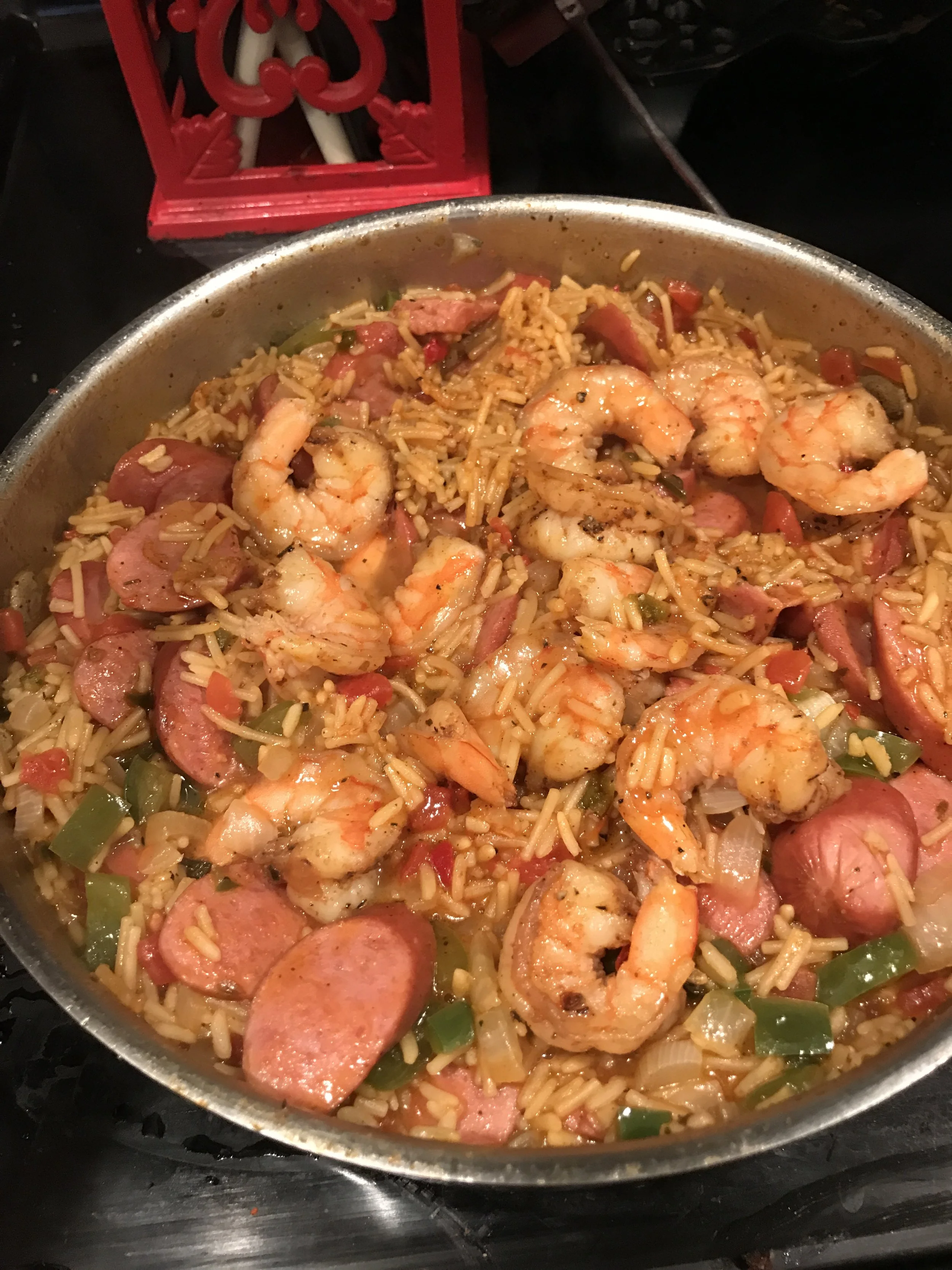 Shrimp and sausage jambalaya with rice, diced green and red bell peppers, onions, and seasonings in a skillet.