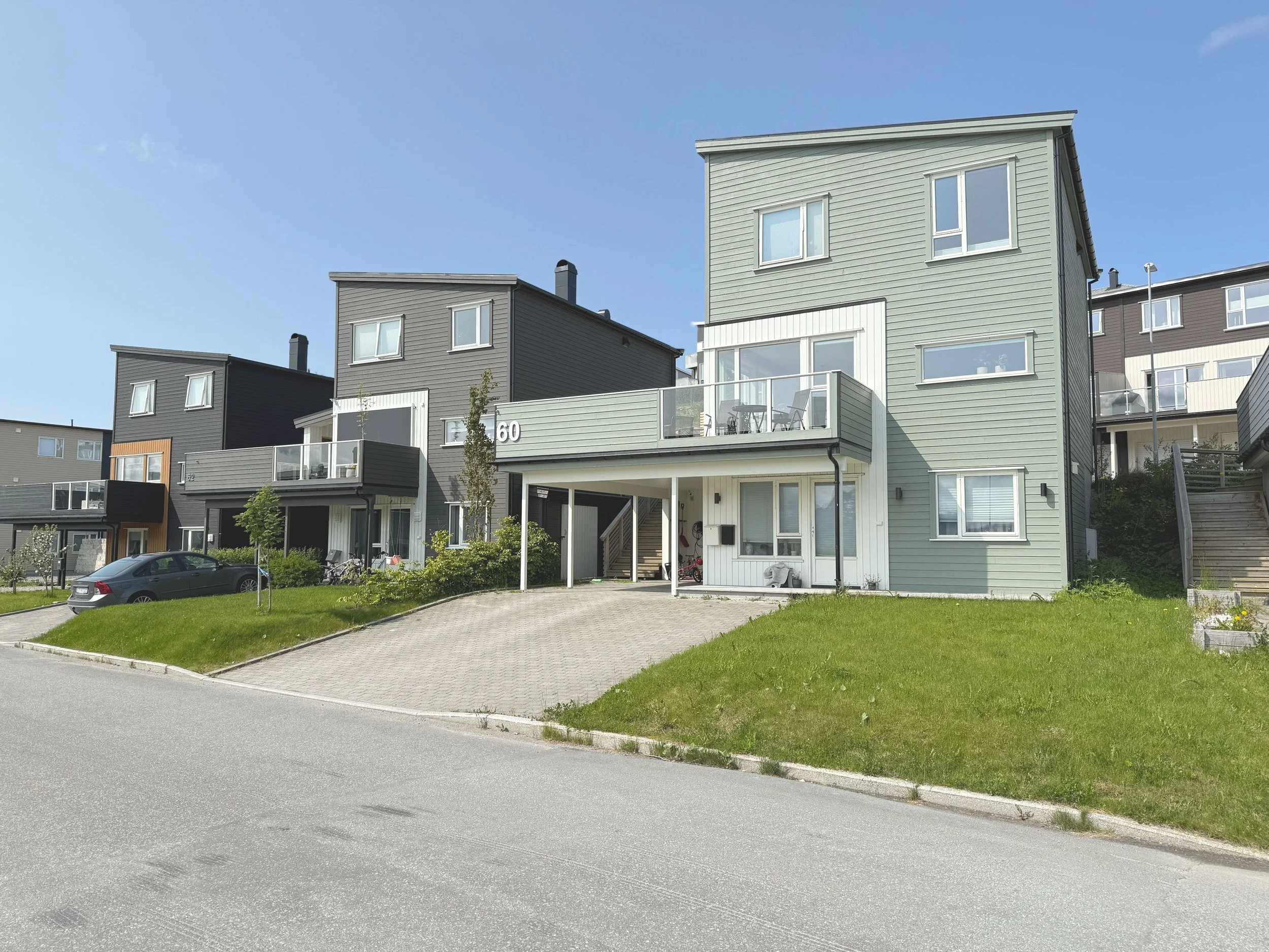 Eneboliger med moderne arkitektur, fargene grå og lysegrønn, med balkonger og store vinduer, omgitt av grønt område. Utsikt til Børvasstindan.