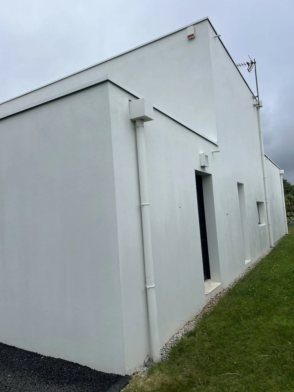 Façade avant intervention, recouverte de traces rouges et de salissures vertes, typiques du climat humide de Sautron près de Nantes.