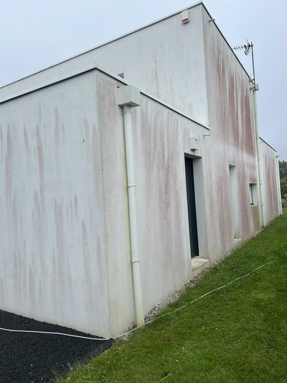 Application du traitement professionnel sur la façade, pour éliminer durablement les algues rouges tout en préservant l’enduit existant.