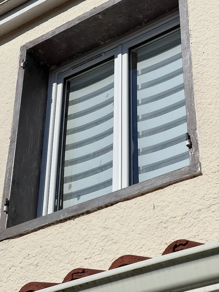 Fenêtre encadrée d’un contour métallique, entièrement décapé puis repeint, sur la façade rénovée de cette maison située à Saint Sébastien sur Loire.
