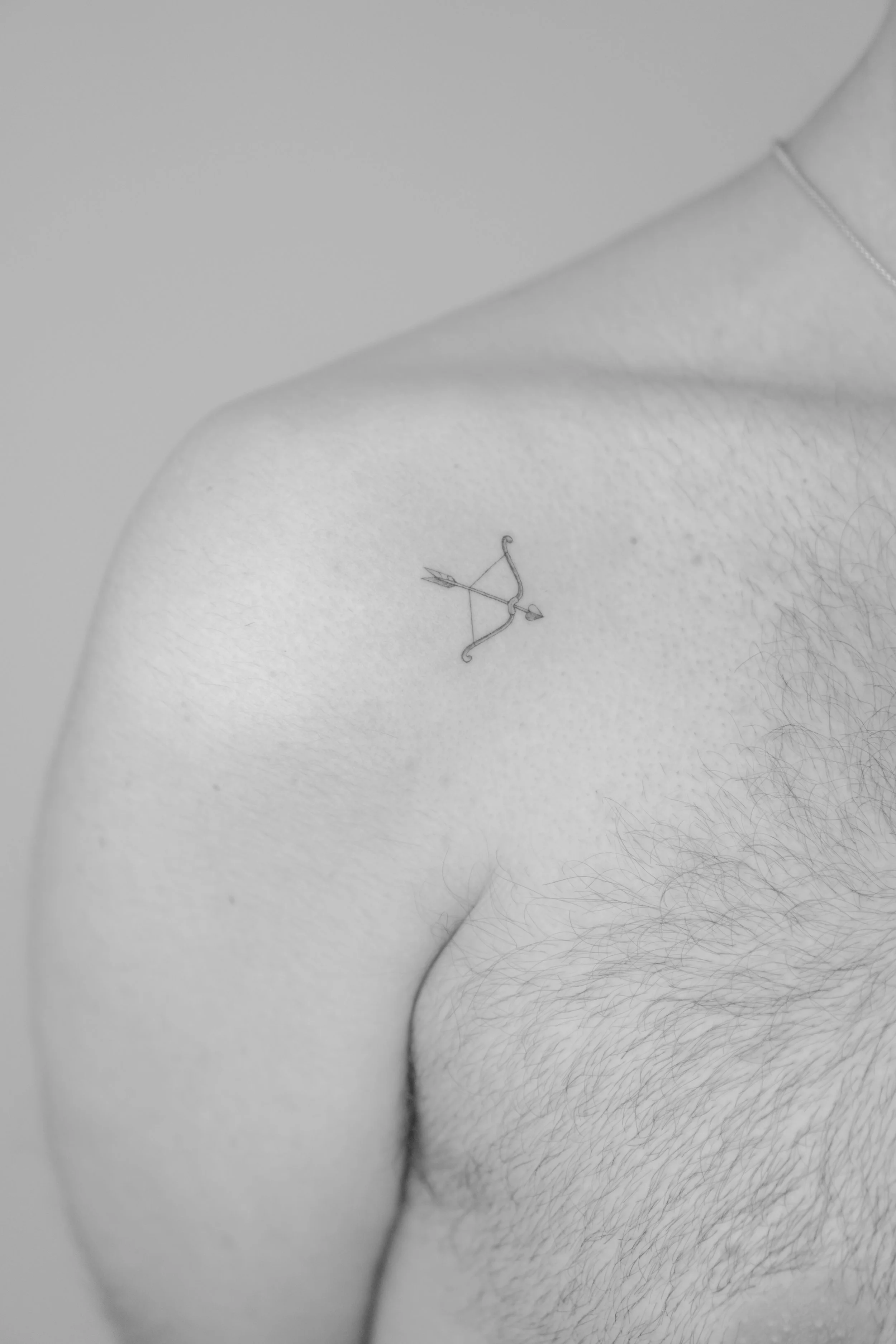 Tatuaje de un arco y flecha en el costado de un hombre con vello corporal.