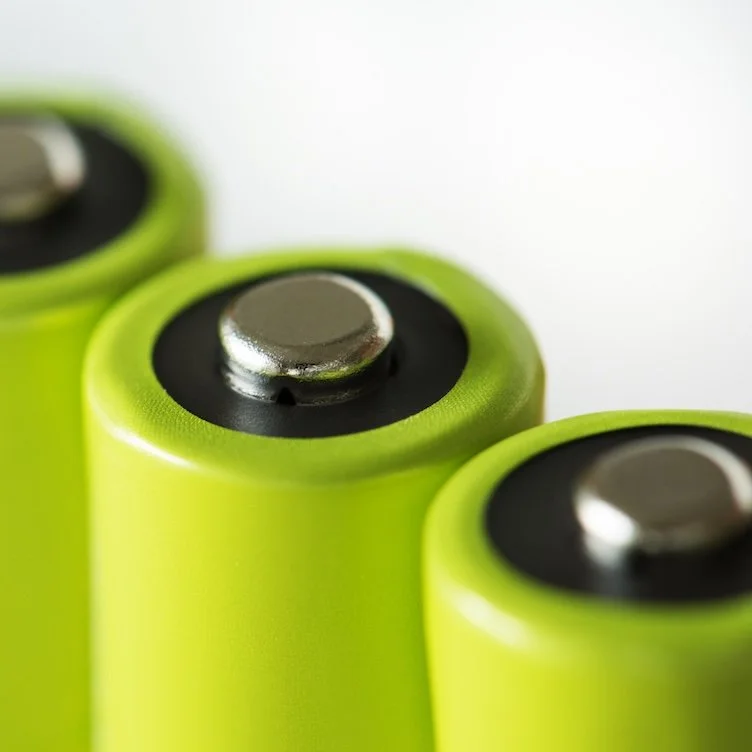 Close-up of three green rechargeable batteries showing their metal positive terminals.