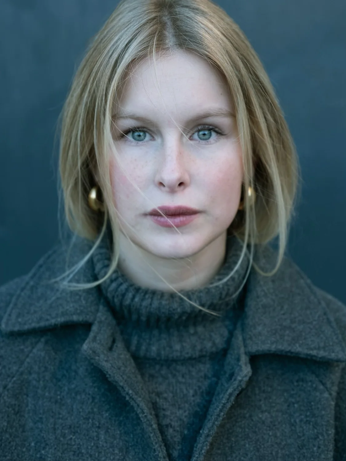 gotland pictures film casting - young woman with blue eyes and blond hair. Golden ear-rings and a grey wool coat.