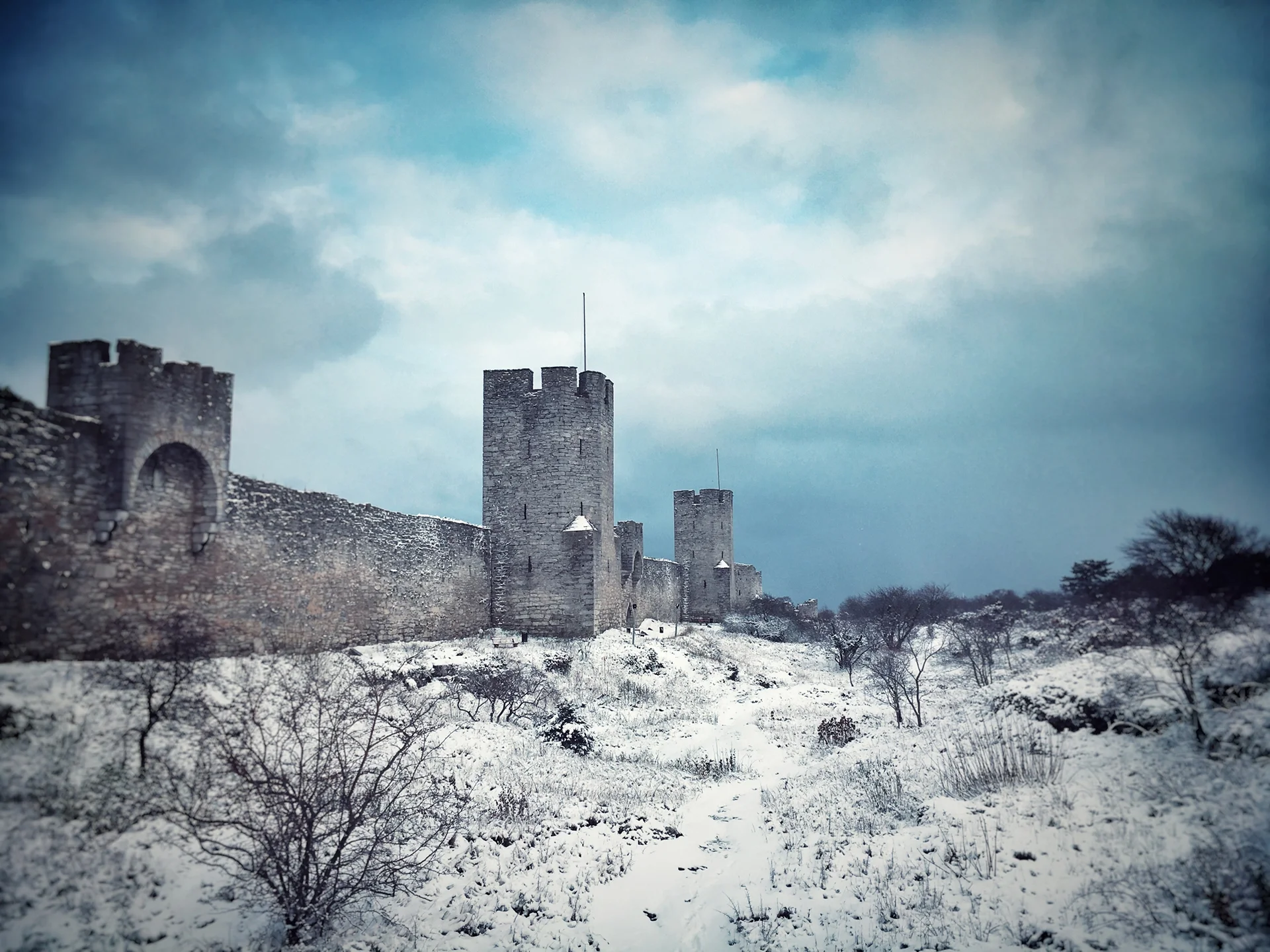 Film Location in Sweden - The medieval ring wall of the World Heritage city of Visby. Snowy ground and cloudy blue sky