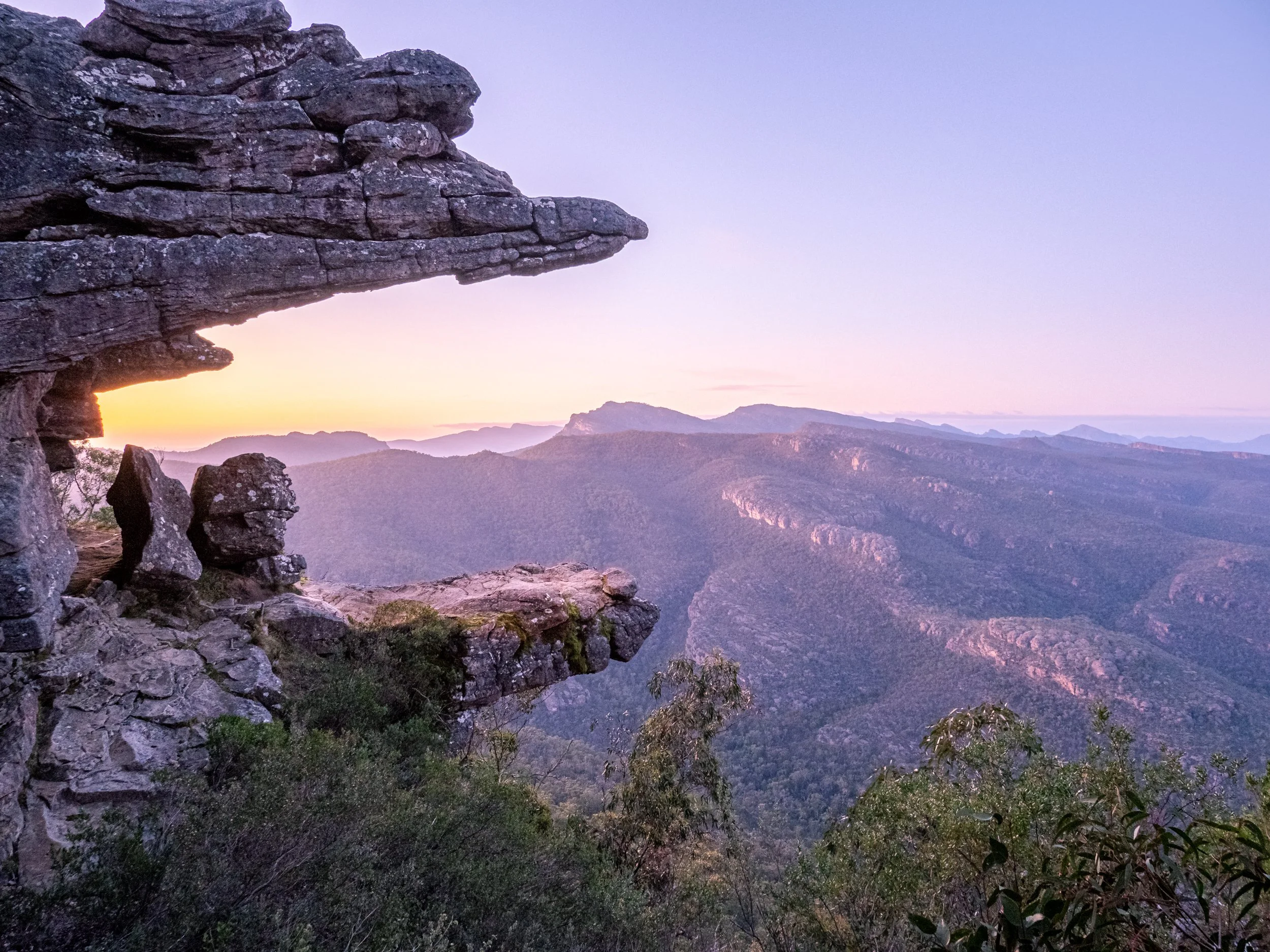 Sunset over a mountain range with rocky outcrop in foreground
