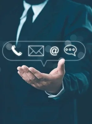 Businessperson in suit holding hand out with digital icons of phone, email, at symbol, and chat bubble projected above