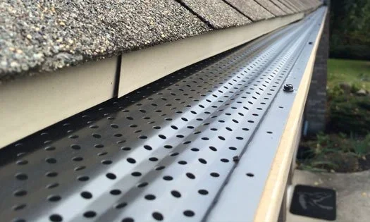 Close-up of a perforated metal gutter installed along the roof edge.