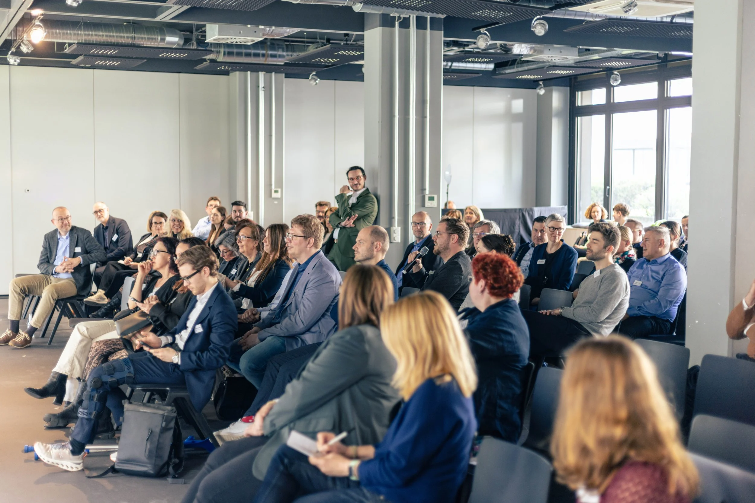 Menschen sitzen in einem Konferenzraum und hören einem Vortrag zu.