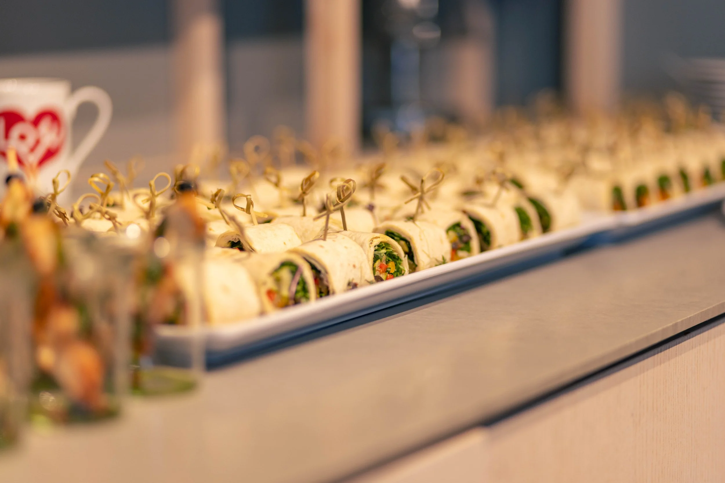 Buffetplatte mit mit Wraps gefüllten Snacks, dekorativ auf einer weißen Servierplatte präsentiert.