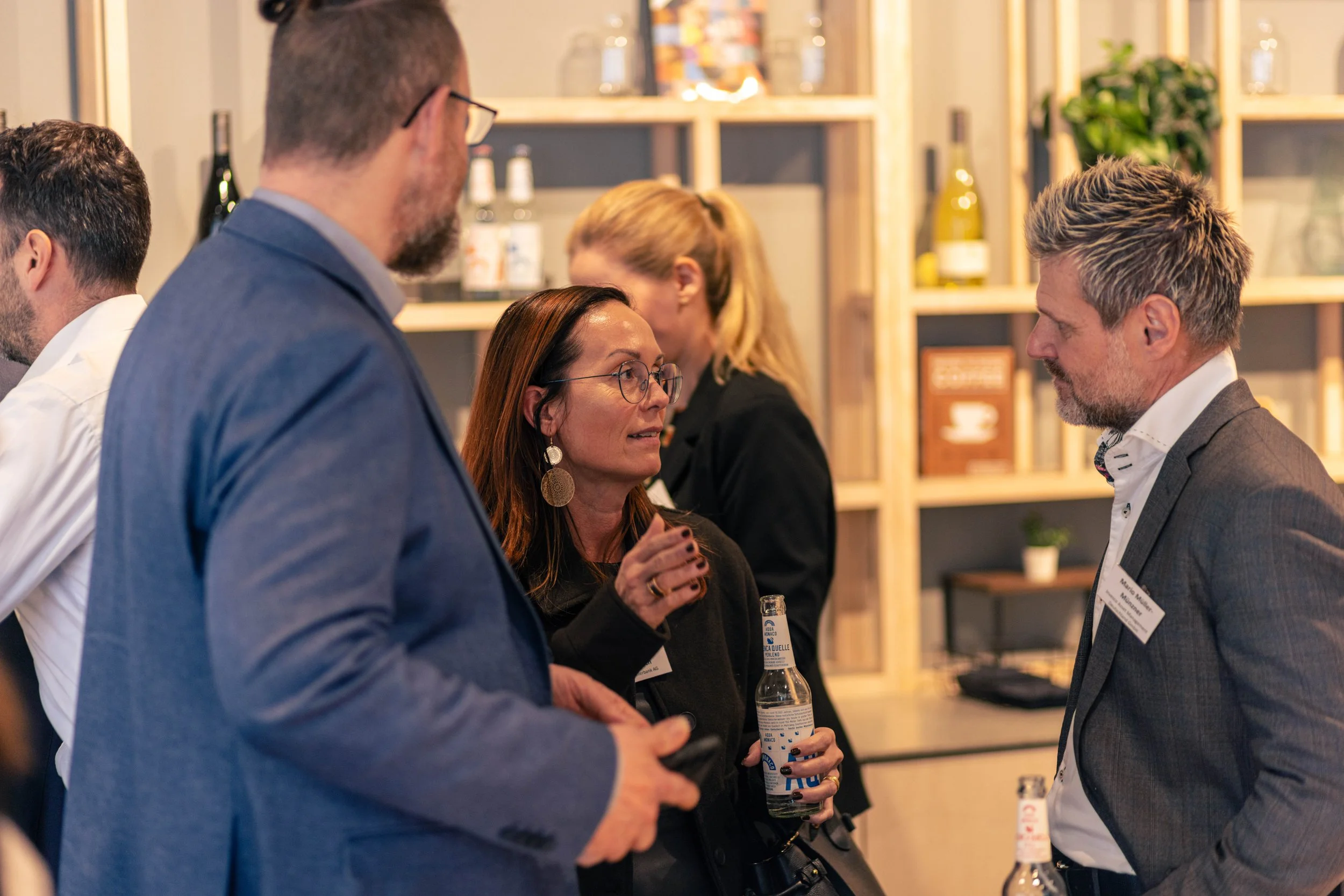 Mehrere Personen im Gespräch bei einer Veranstaltung, im Hintergrund Regale mit Büchern und Dekorationsgegenständen.