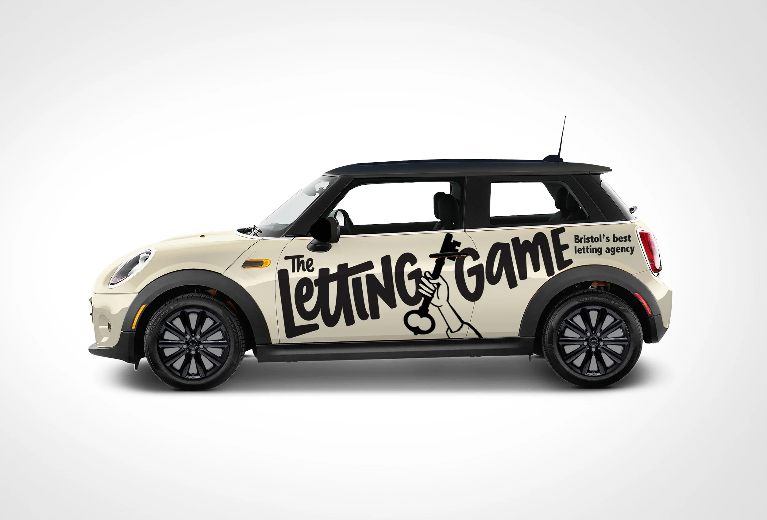A cream-colored Mini Cooper car with black roof and wheels, featuring a large graphic on the side that says 'The Letting Game' with a hand holding a gavel, and smaller text that reads 'Bristol's best letting agency'.