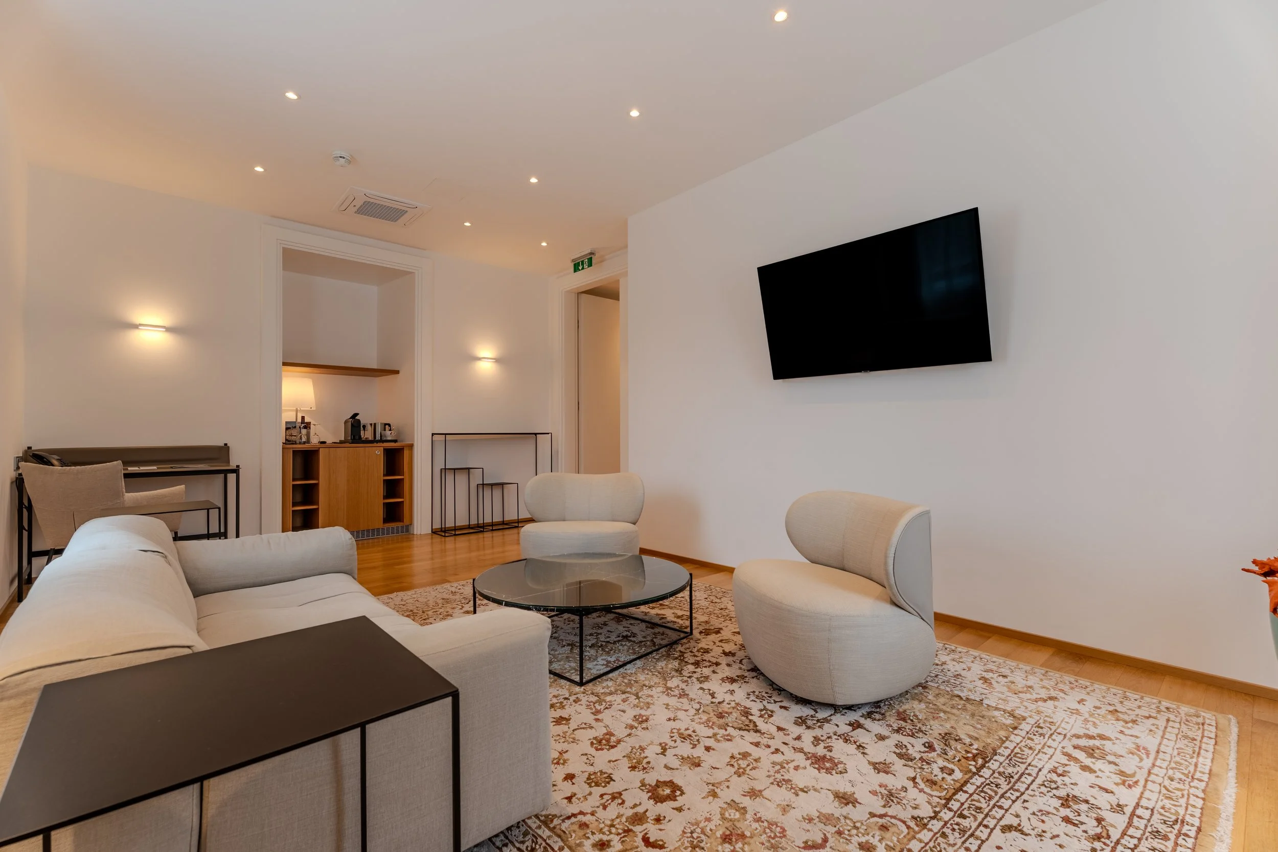 Heller Wohnbereich mit Sofa, Couchtisch, Teppich und angrenzender Küchenzeile im Hintergrund