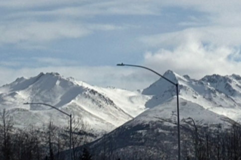 Snow-covered mountains under a cloudy sky in Alaska.