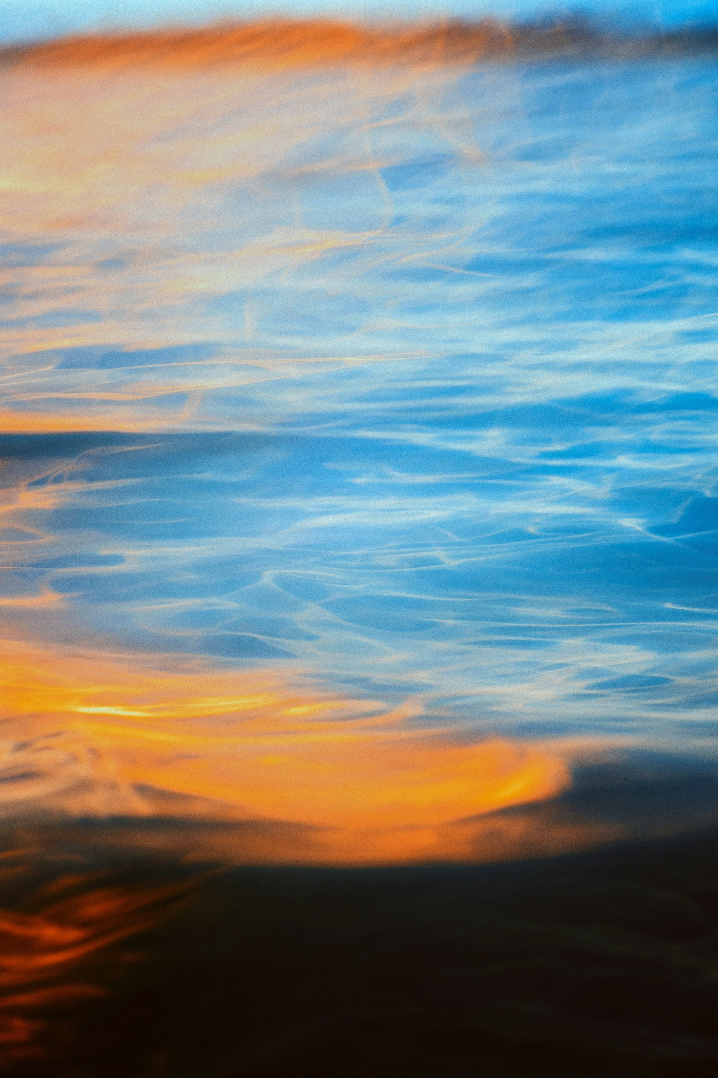 Colorful sky with orange, blue, and yellow hues reflected on water surface.