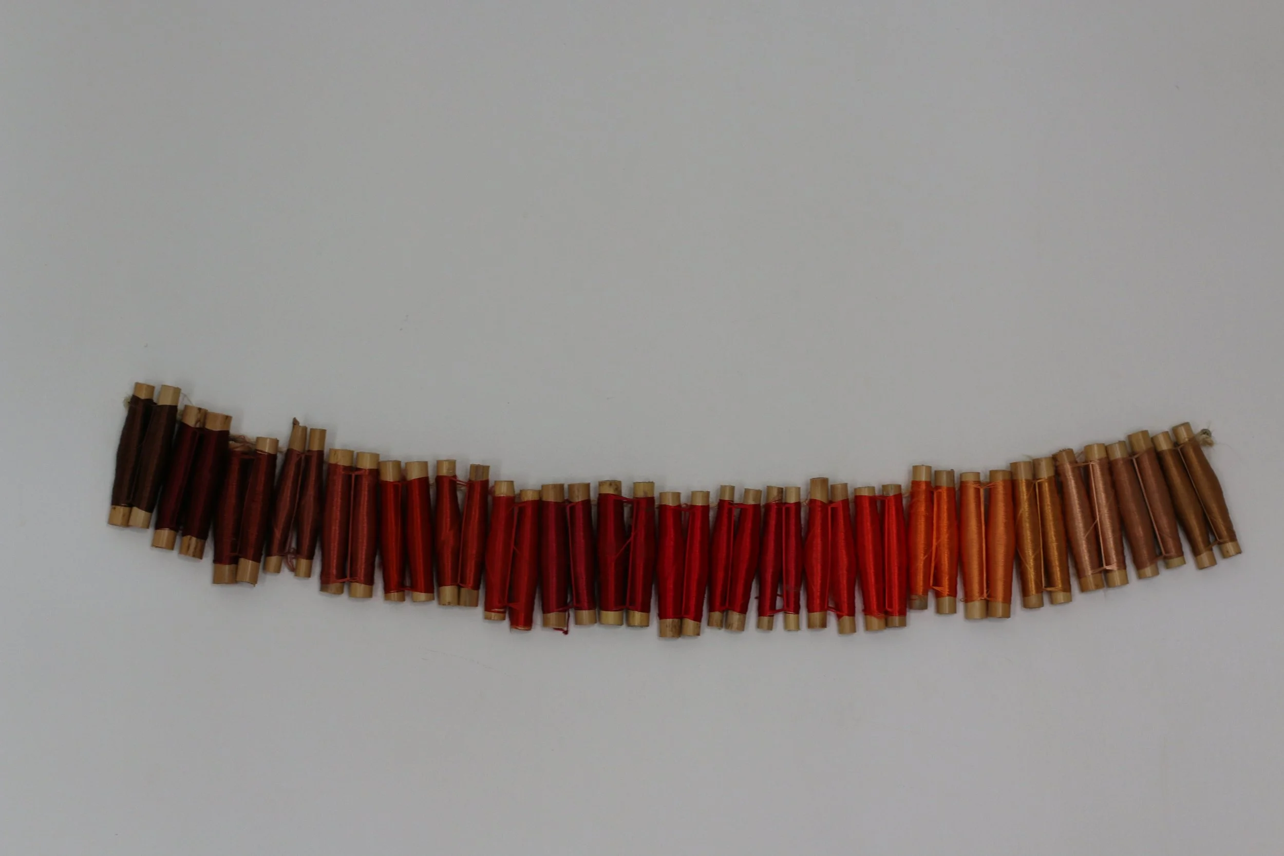 Fil de boutons de différentes nuances de rouge, orange et marron sur fond blanc.