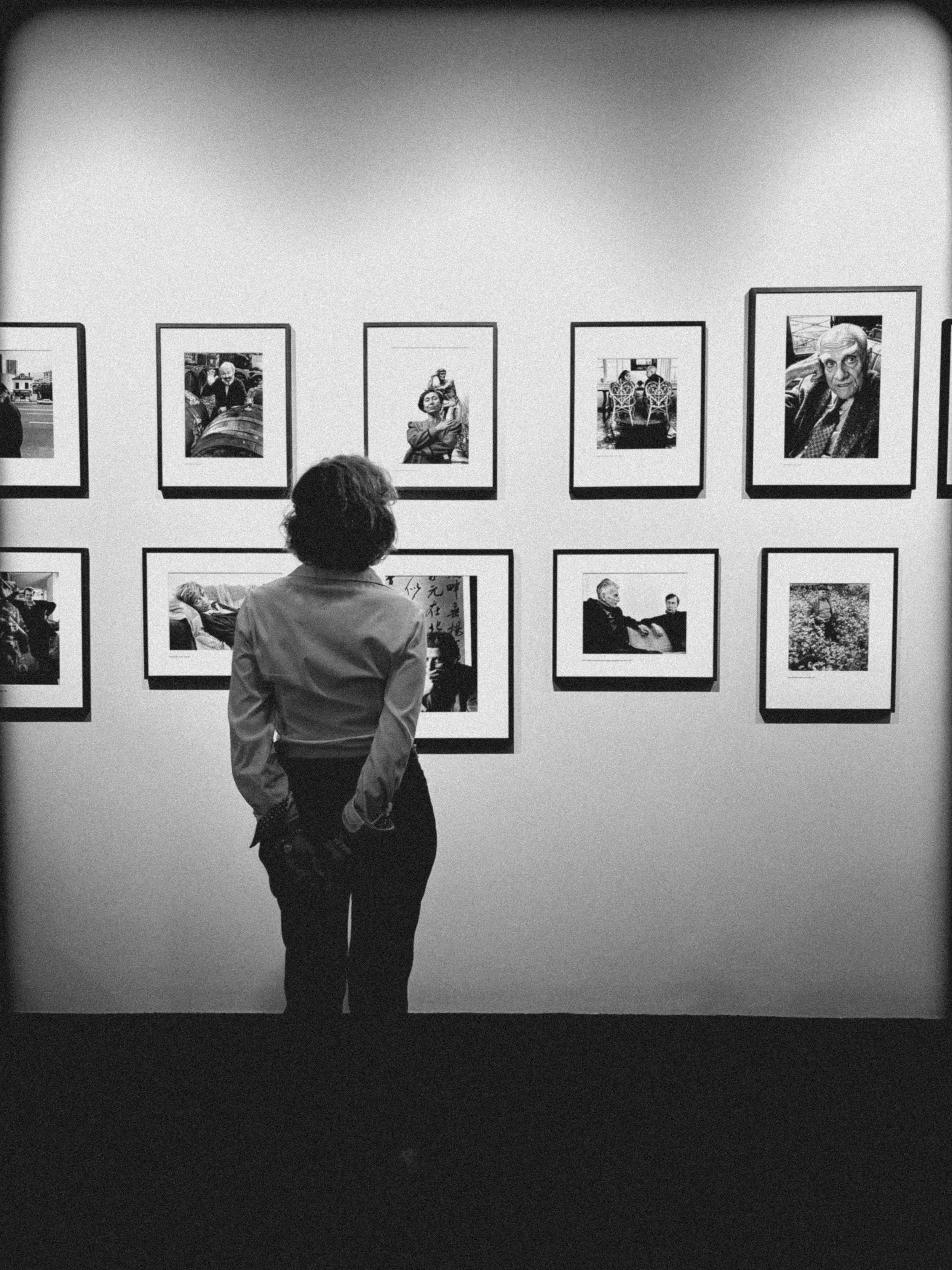 Une personne regarde une galerie de photos en noir et blanc affichées sur un mur.