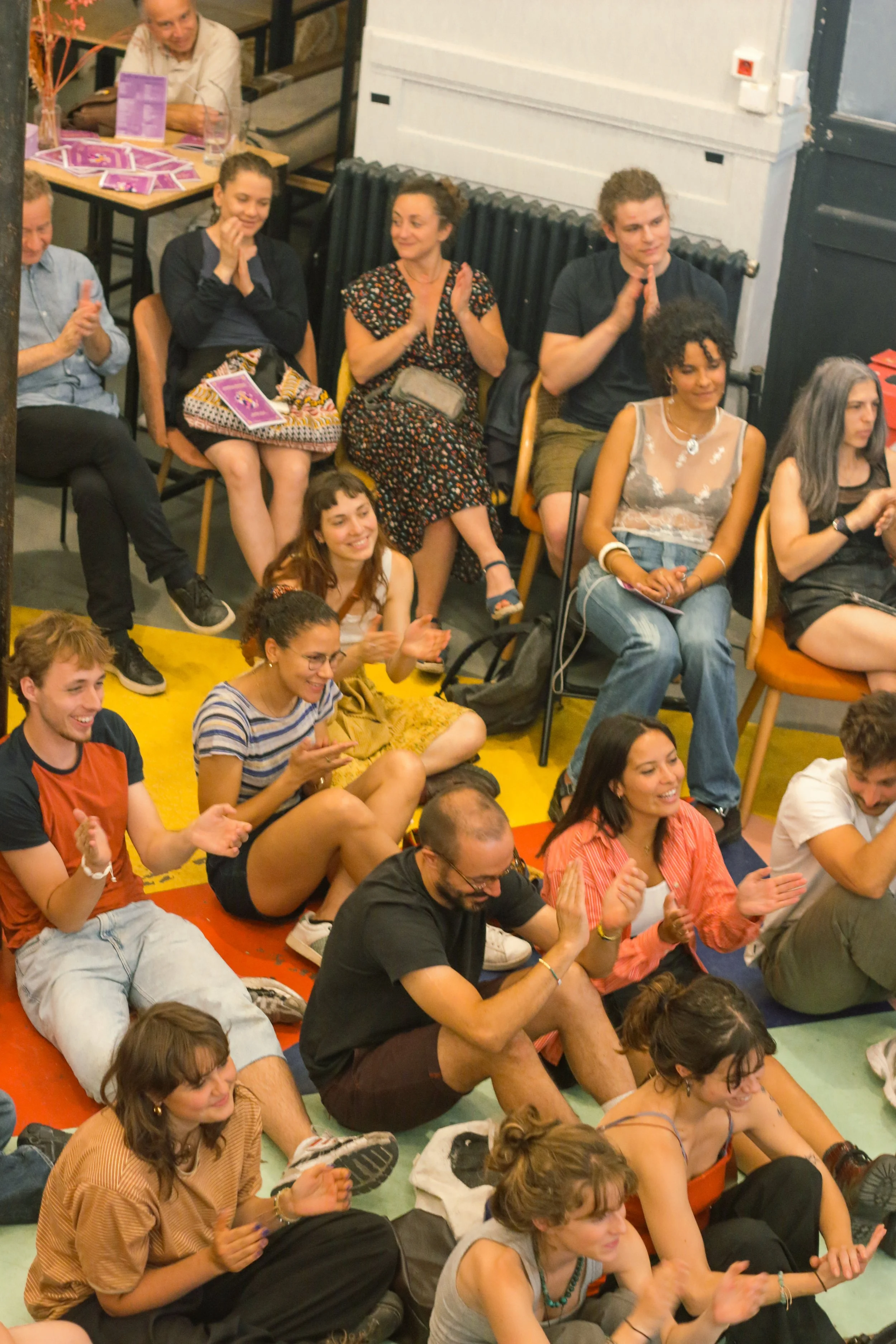 Groupe de personnes souriantes et applaudissant lors d'un événement à l'intérieur.