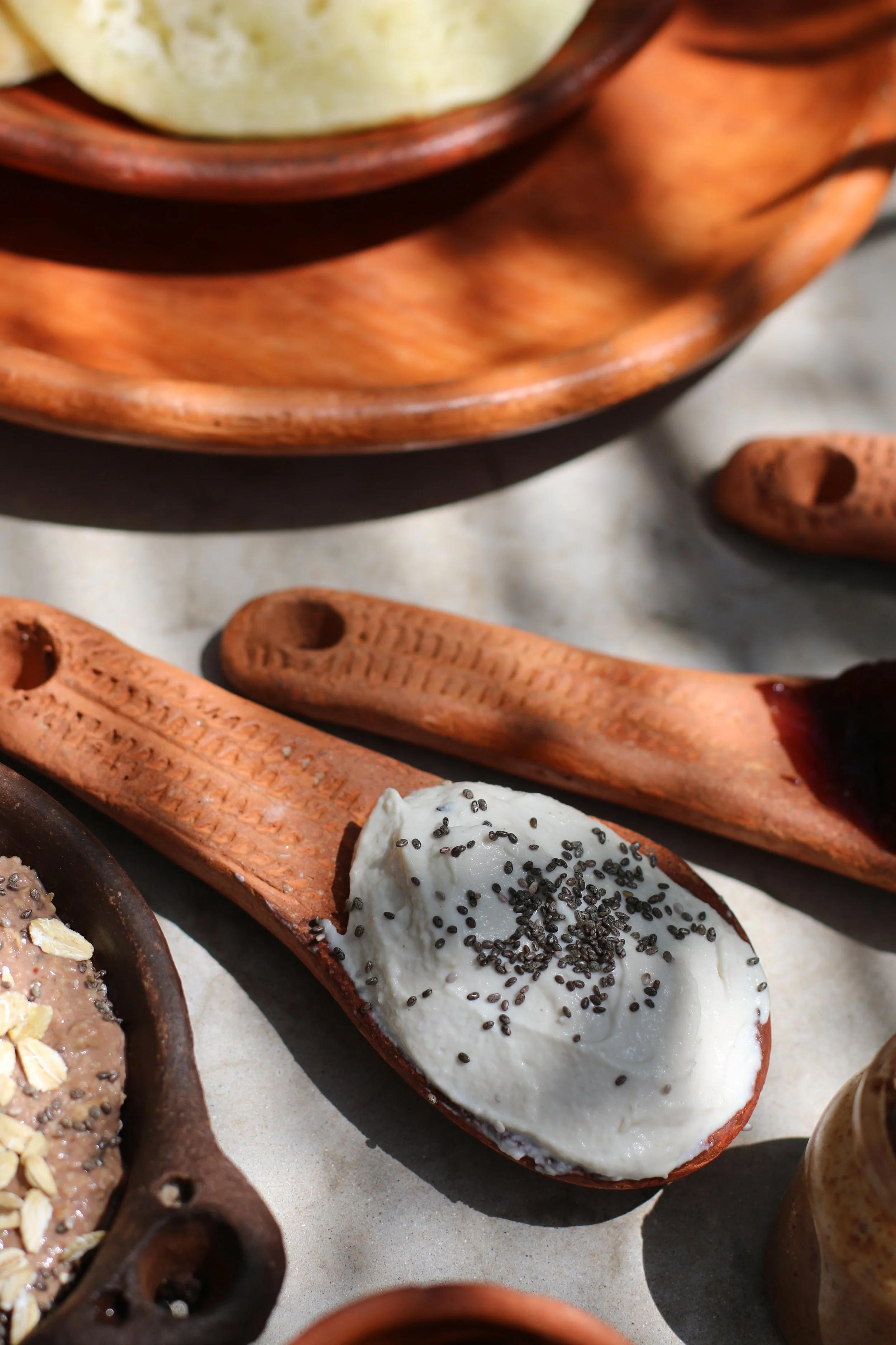 Cuillère en bois avec de la crème ou du yaourt garnie de graines de chia.