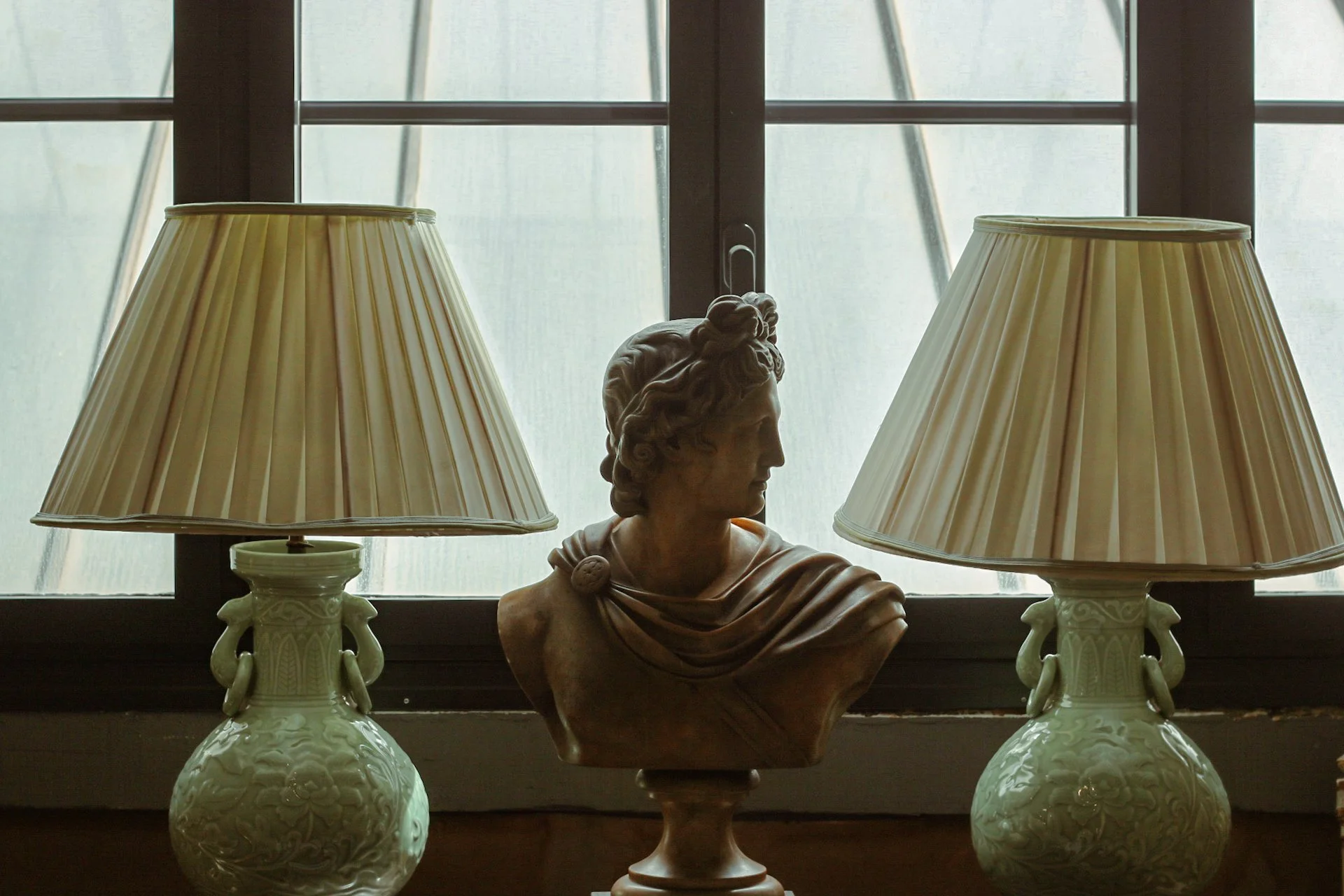 Une reproduction en plâtre d'un bust de femme, placée entre deux lampes à base en céramique avec abat-jour en tissu.