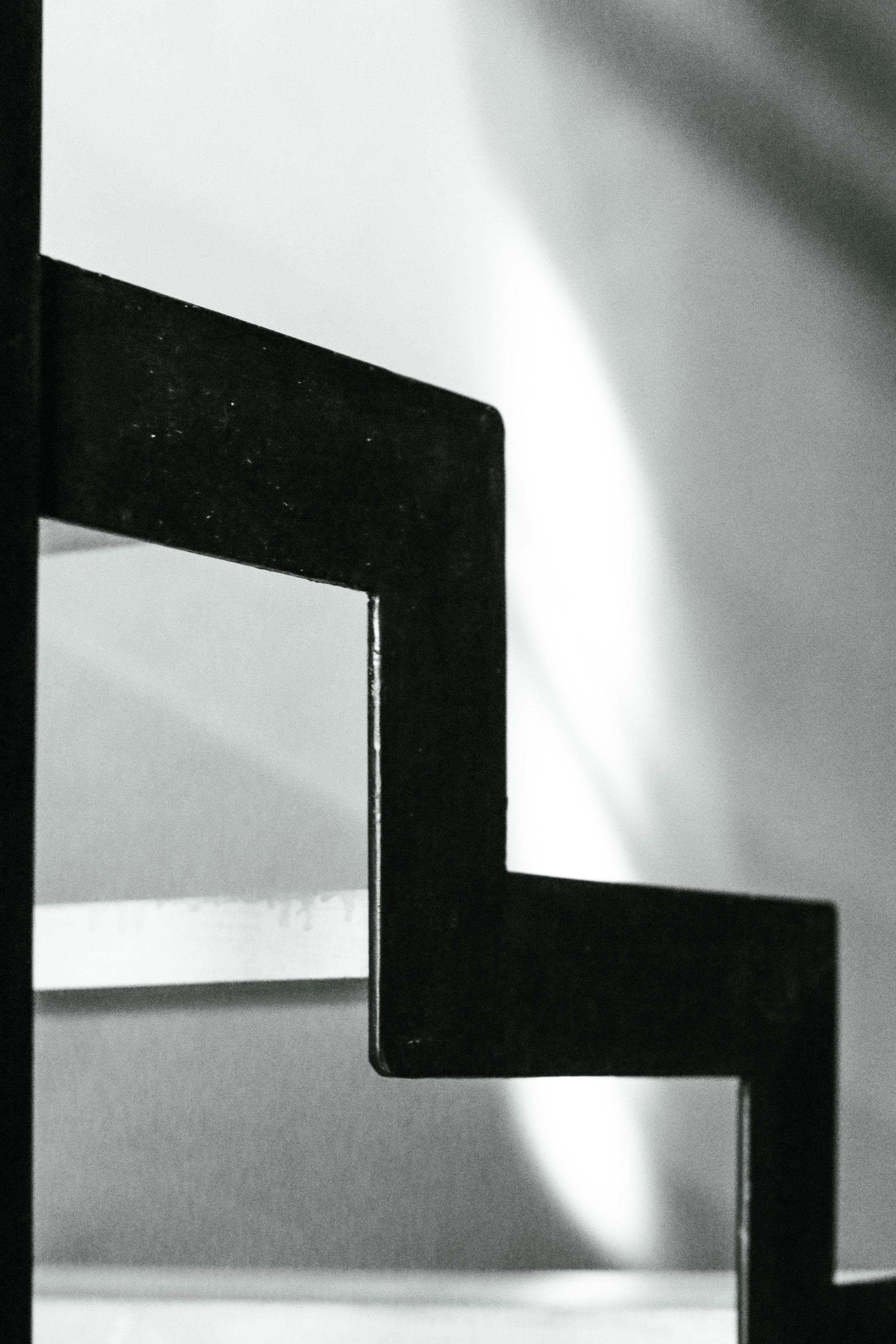 Photo en noir et blanc d'une rampe d'escalier en métal, vue en gros plan.