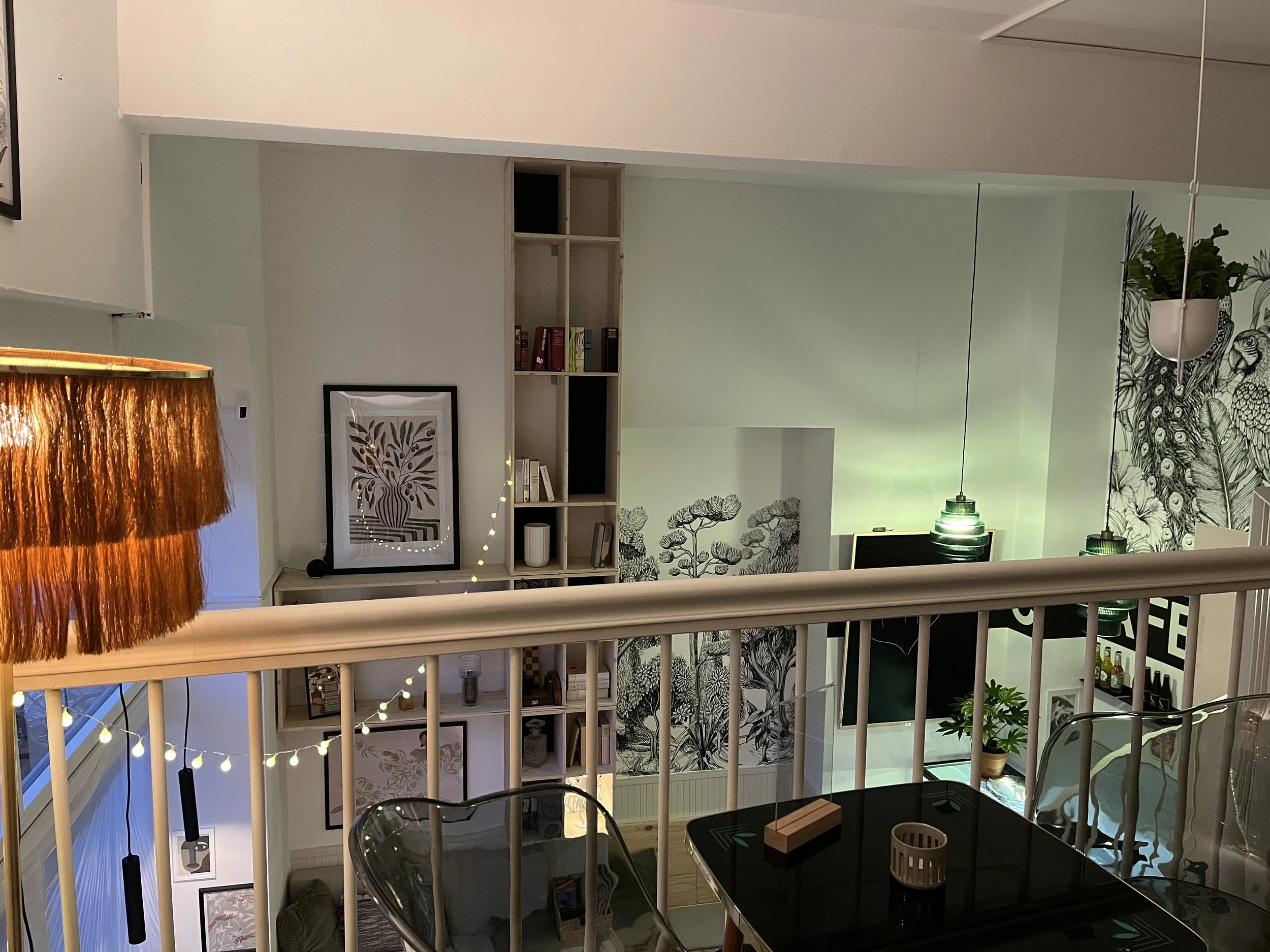 Ein Blick in eine moderne, gemütliche Innenraumgestaltung mit offenen Regalen, dekorativen Bildern, Pflanzen und stromsparenden Lampen.