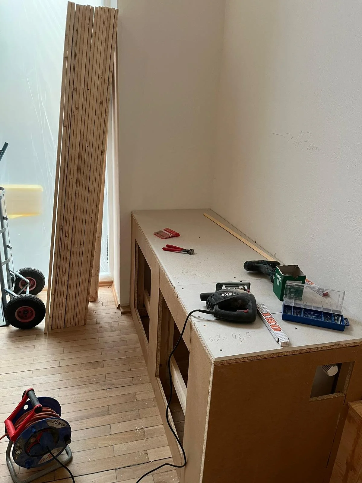 Innenraum einer Werkstatt im Bau, mit Werkbänken, Werkzeugen und Baumaterialien.