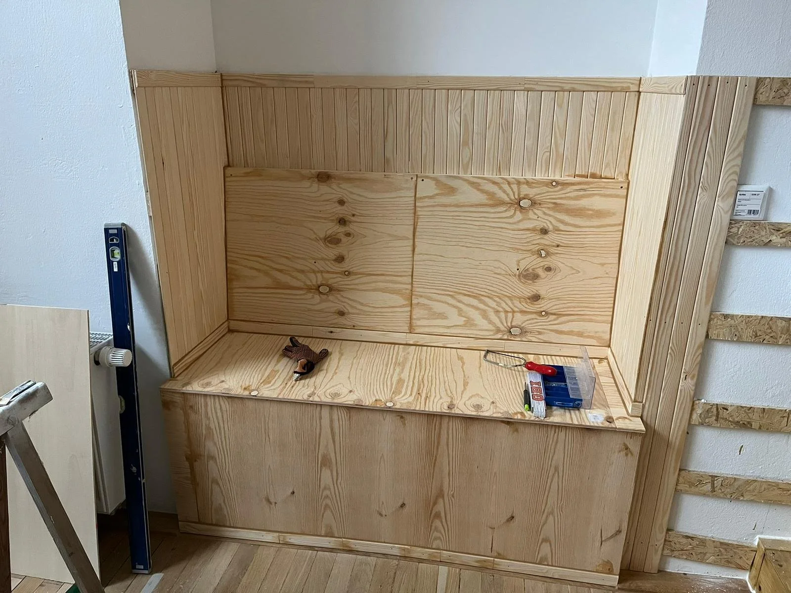 Holzregale und eine Kiste, die in einem Raum gebaut werden, mit Werkzeugen auf den Oberflächen.