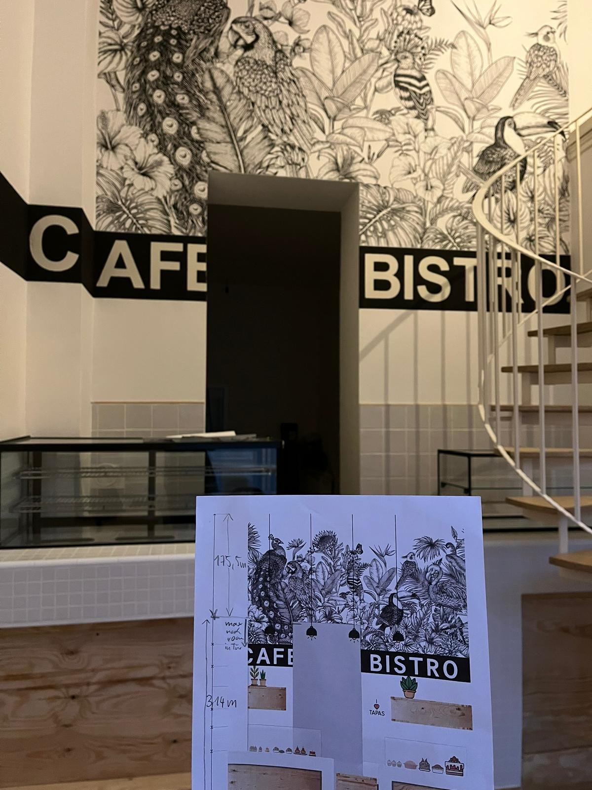 Schwarz-weiß Wandkunst mit Vögeln und Pflanzen, Schriftzug 'CAFÉ BISTRO', Inneneinrichtung mit Treppe, Theatposter mit Vogelzeichnung auf Pappkarte