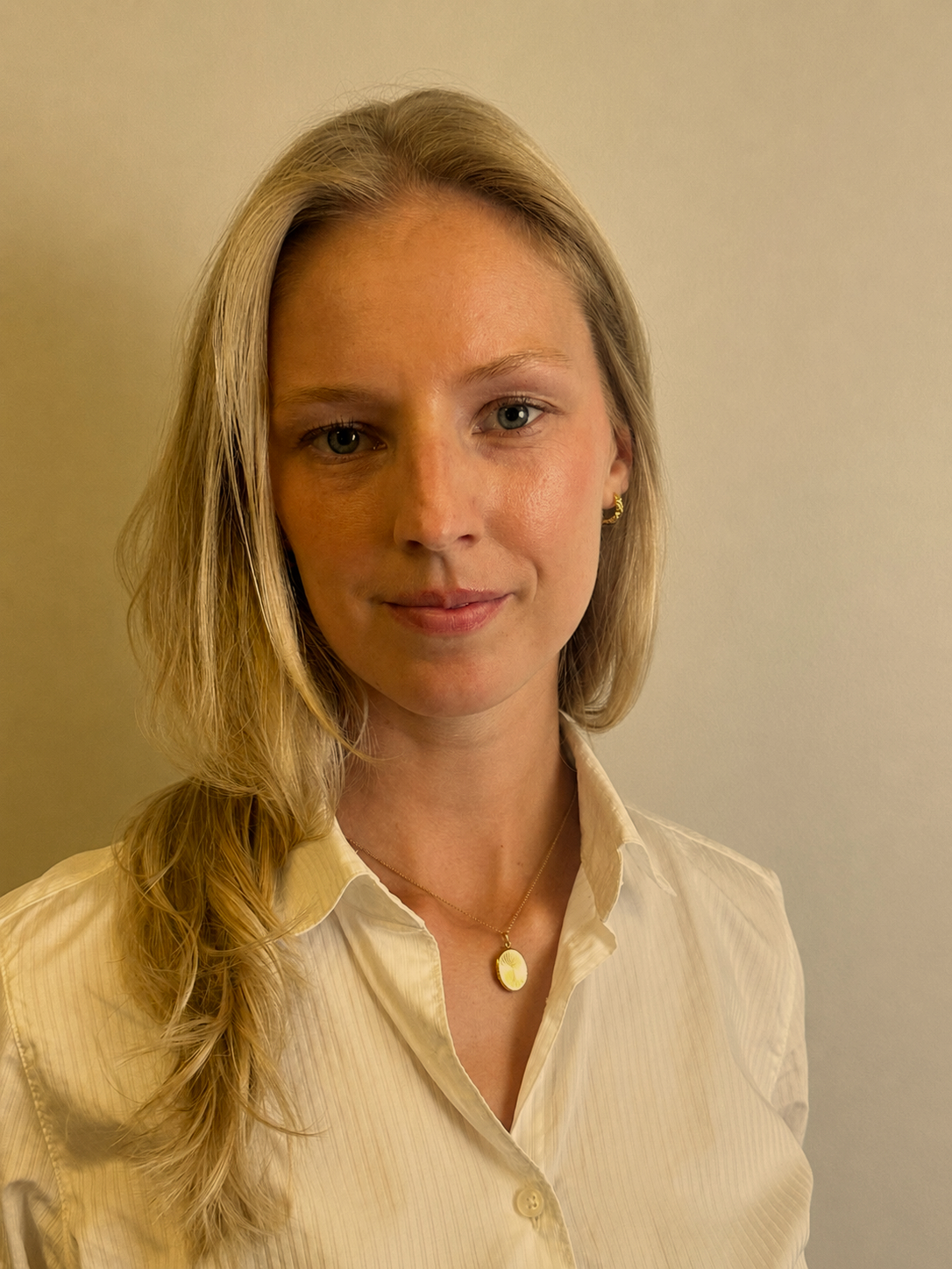 A young woman with shoulder-length blonde hair wearing a black top, looking at the camera with a slight smile against a plain background.