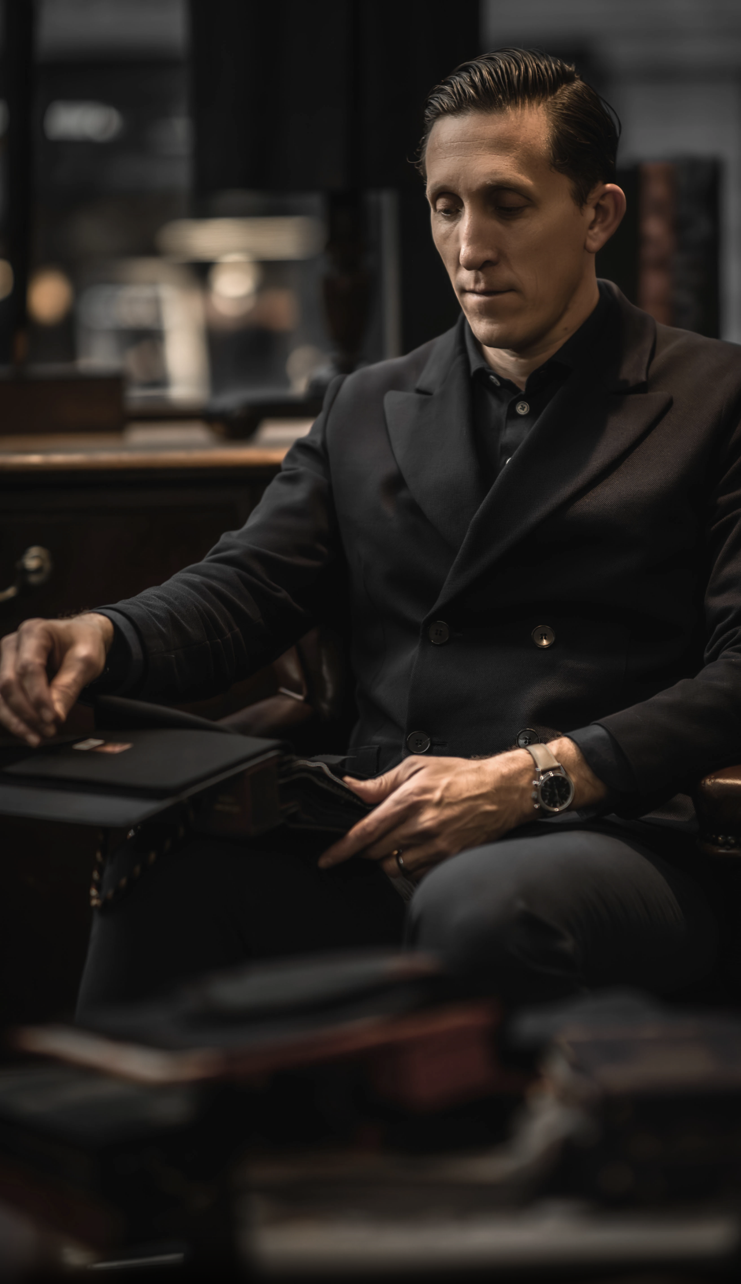 James Barclay, Team Principal of Jaguar TCS Racing, seated inside the historic Henry Poole & Co store on Savile Row, London, reviewing luxury fabric swatches for his bespoke suit — blending heritage tailoring with modern motorsport style.
