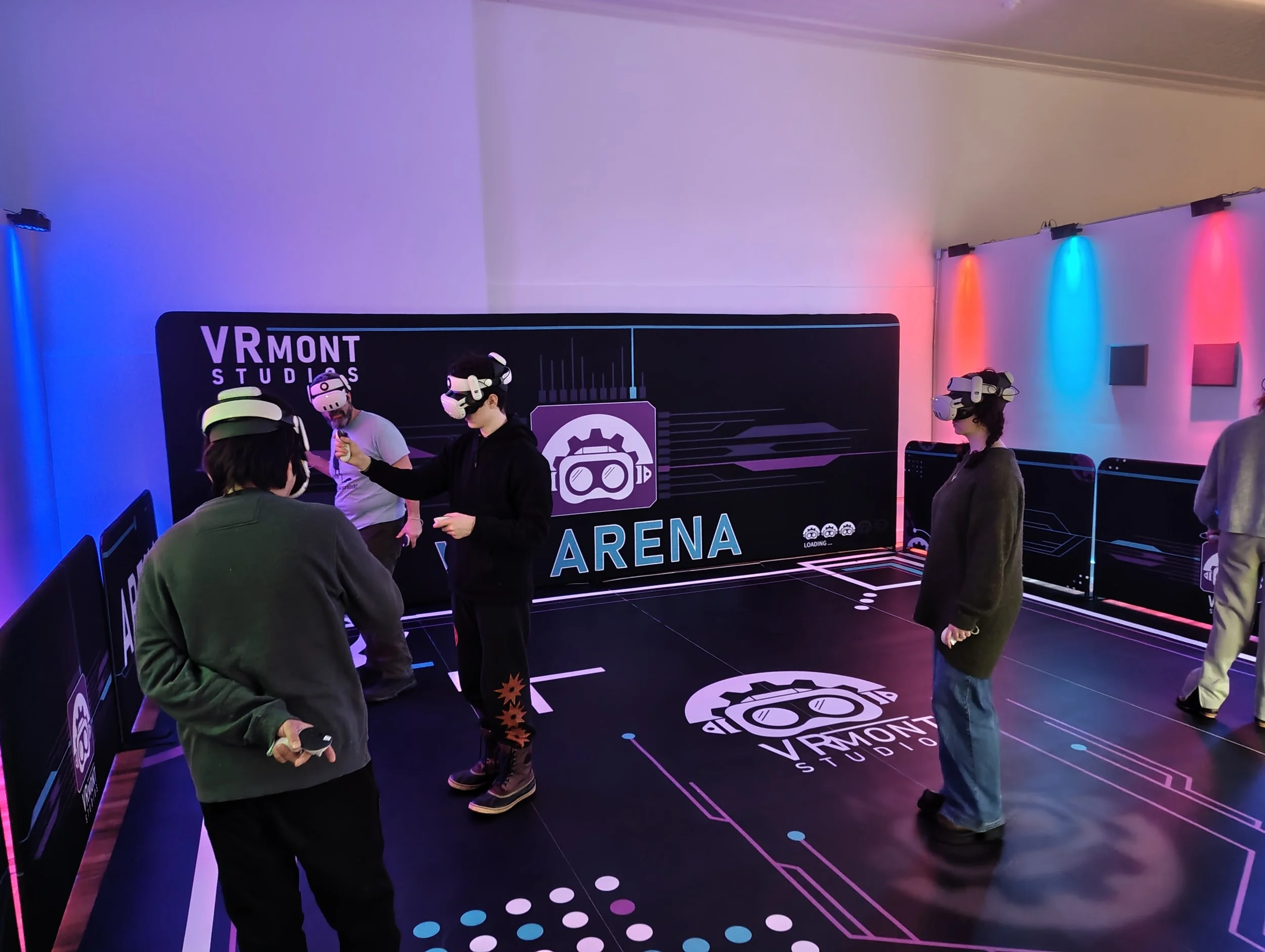 People wearing VR headsets in an VR gaming arena, with practice barriers and colorful lighting.