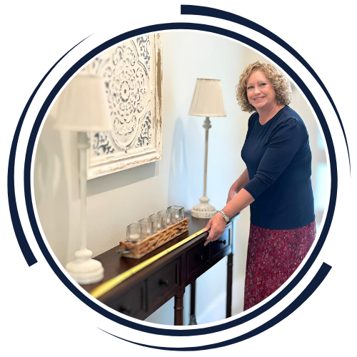 Woman measuring a console table with a tape measure in a living room.