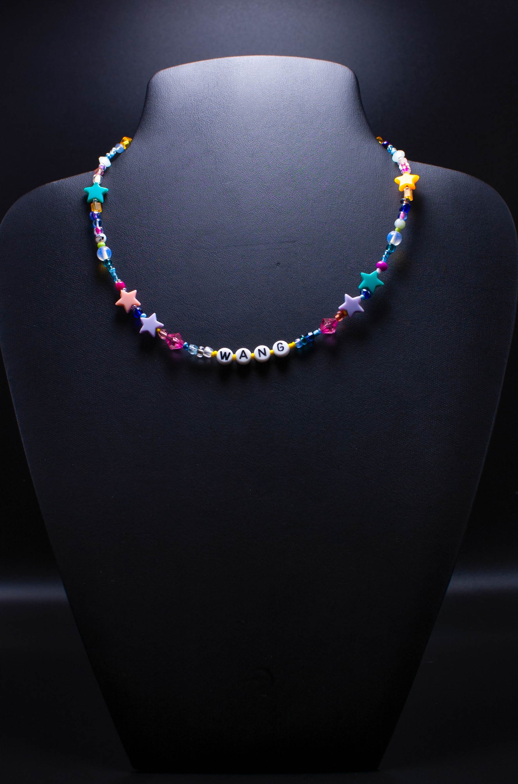 Colorful beaded necklace with letter beads spelling 'WANG' displayed on a black mannequin bust