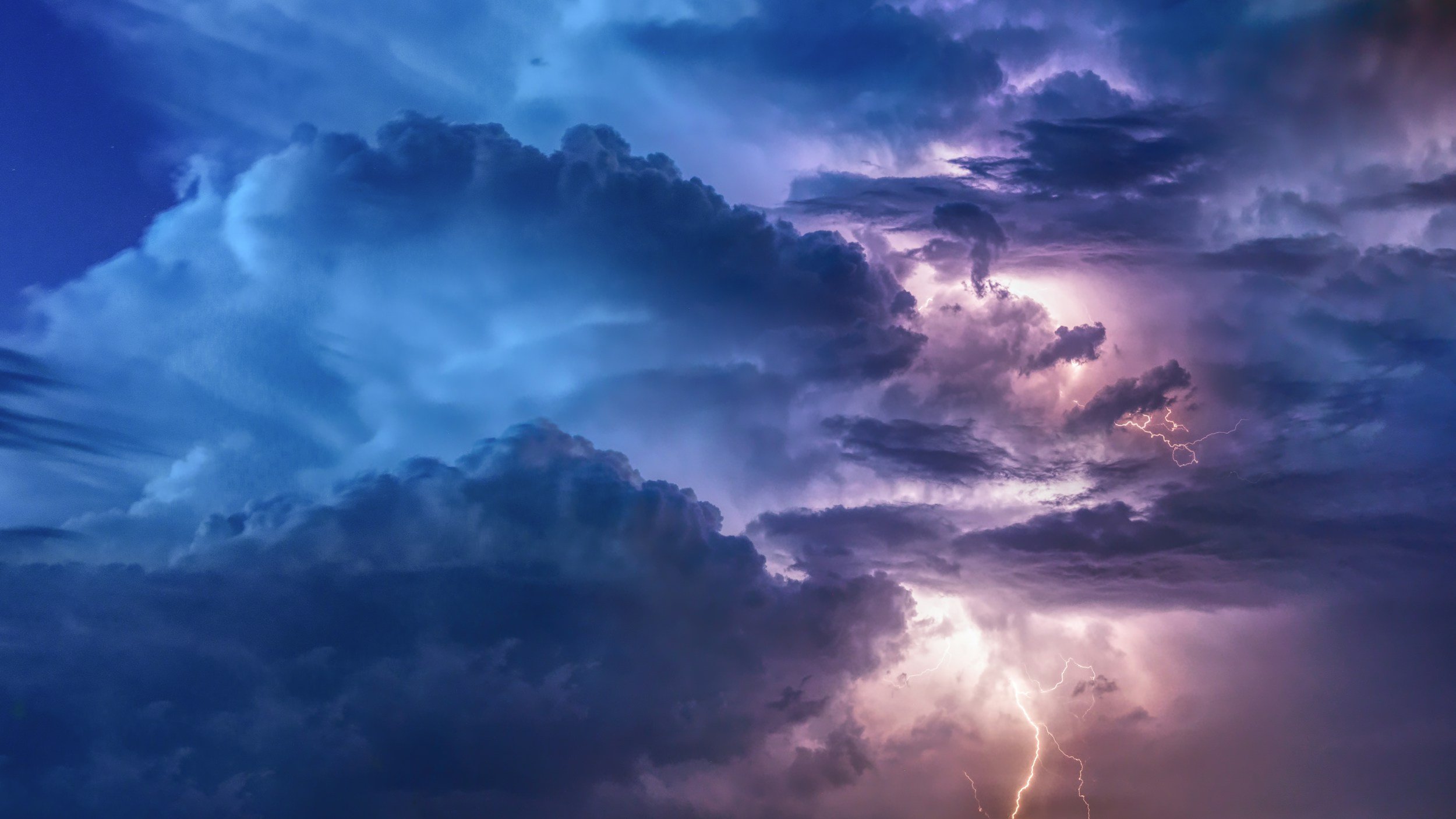 blue and purple clouds in a storm with lightning striking