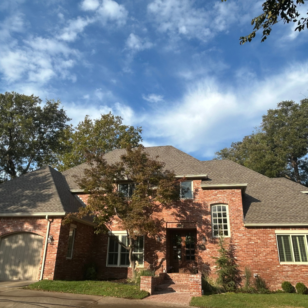 Brick home in Tulsa with a newly installed dark shingle roof by Miller Roof & Exteriors