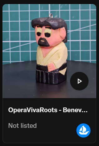 Statua di un uomo con barba e cappello, vestito con una tunica gialla e pantaloni neri, posata su una superficie con sfondo di piastrelle blu.