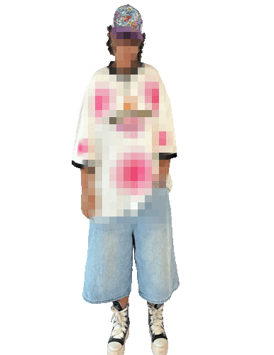 A person standing against a black background, wearing a colorful beanie, a white oversized t-shirt with pink and red abstract patterns, baggy light blue jeans, and black and white sneakers, with their face blurred for privacy.