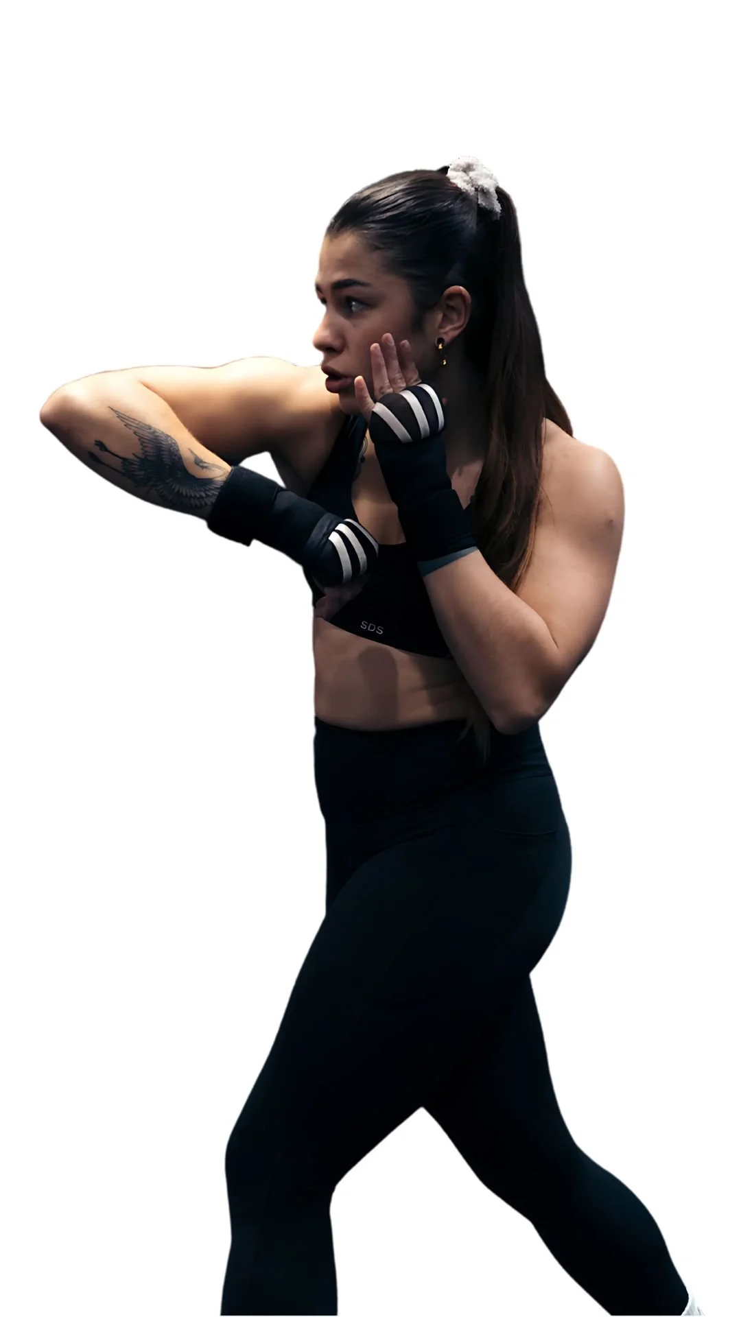 Une femme en tenue de sport, portant des gants de boxe, en position de combat ou de préparation à un combat, avec un fond blanc.
