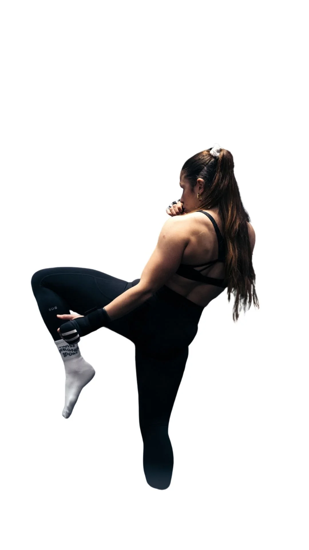 Une femme en tenue de sport en train de faire une pose de kickboxing ou de boxe, tenant une posture de concentration.