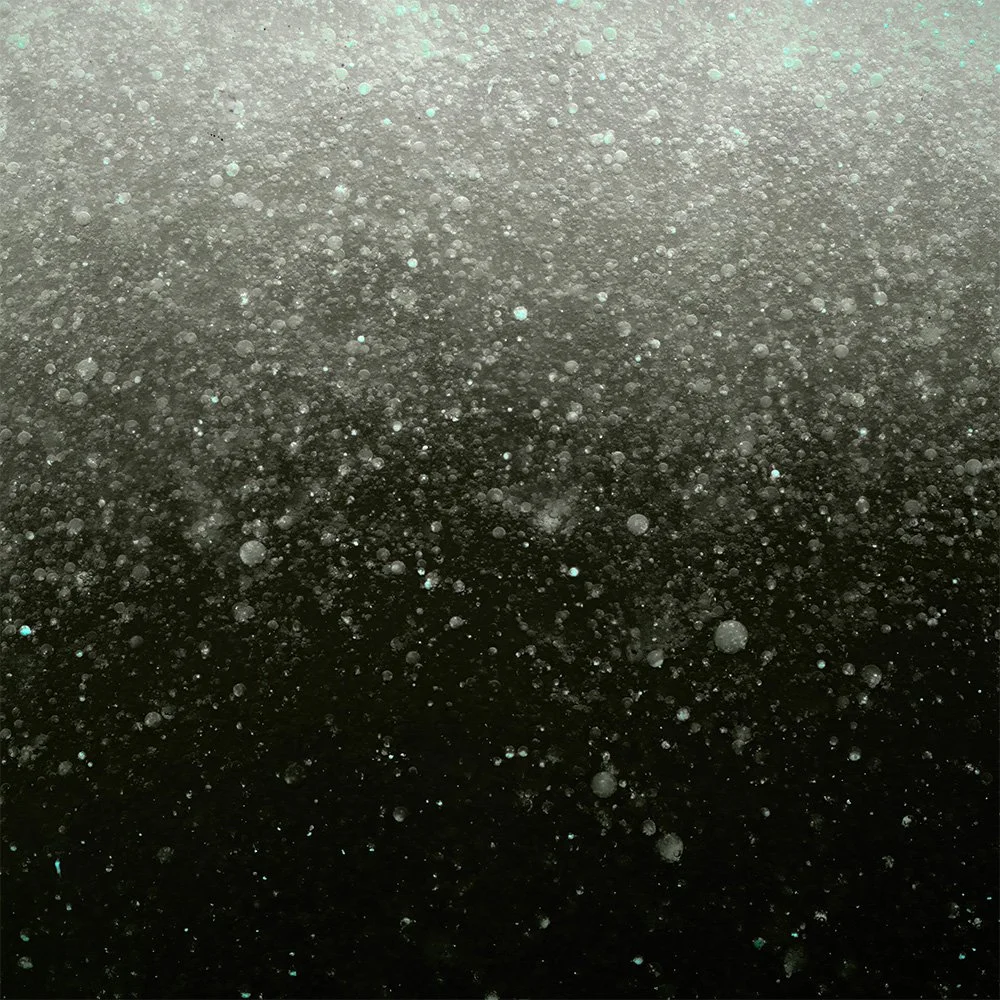 Close-up view of bubbles forming in a dark liquid, with a gradient background from light to dark.