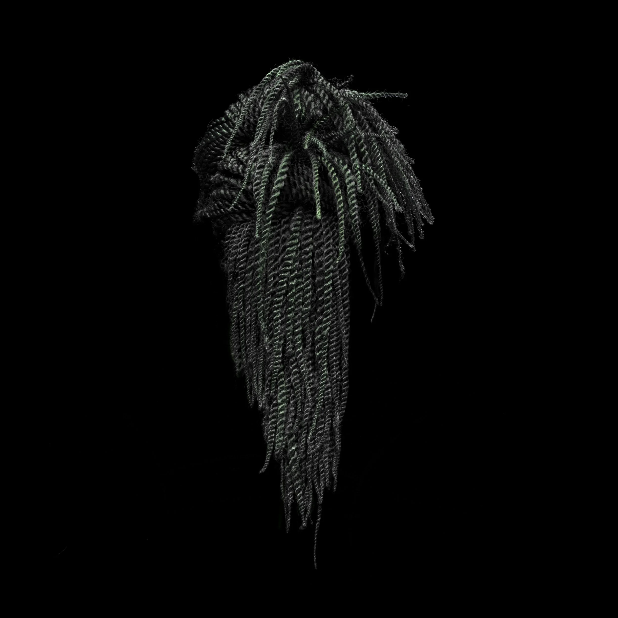 Close-up of dreadlocks with dark and greenish highlights on a black background.
