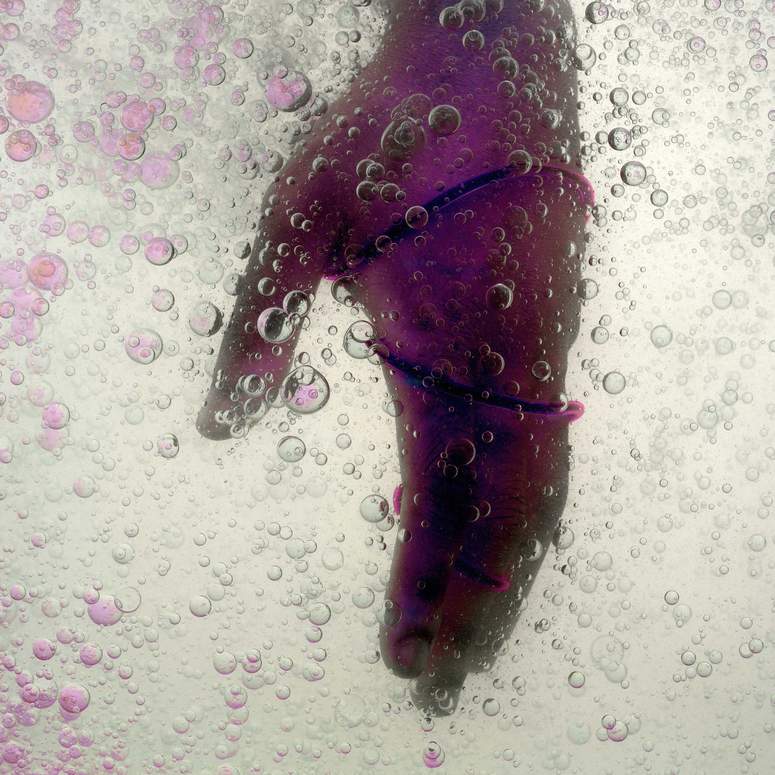 A person wearing colorful swimwear is submerged underwater, surrounded by numerous bubbles.