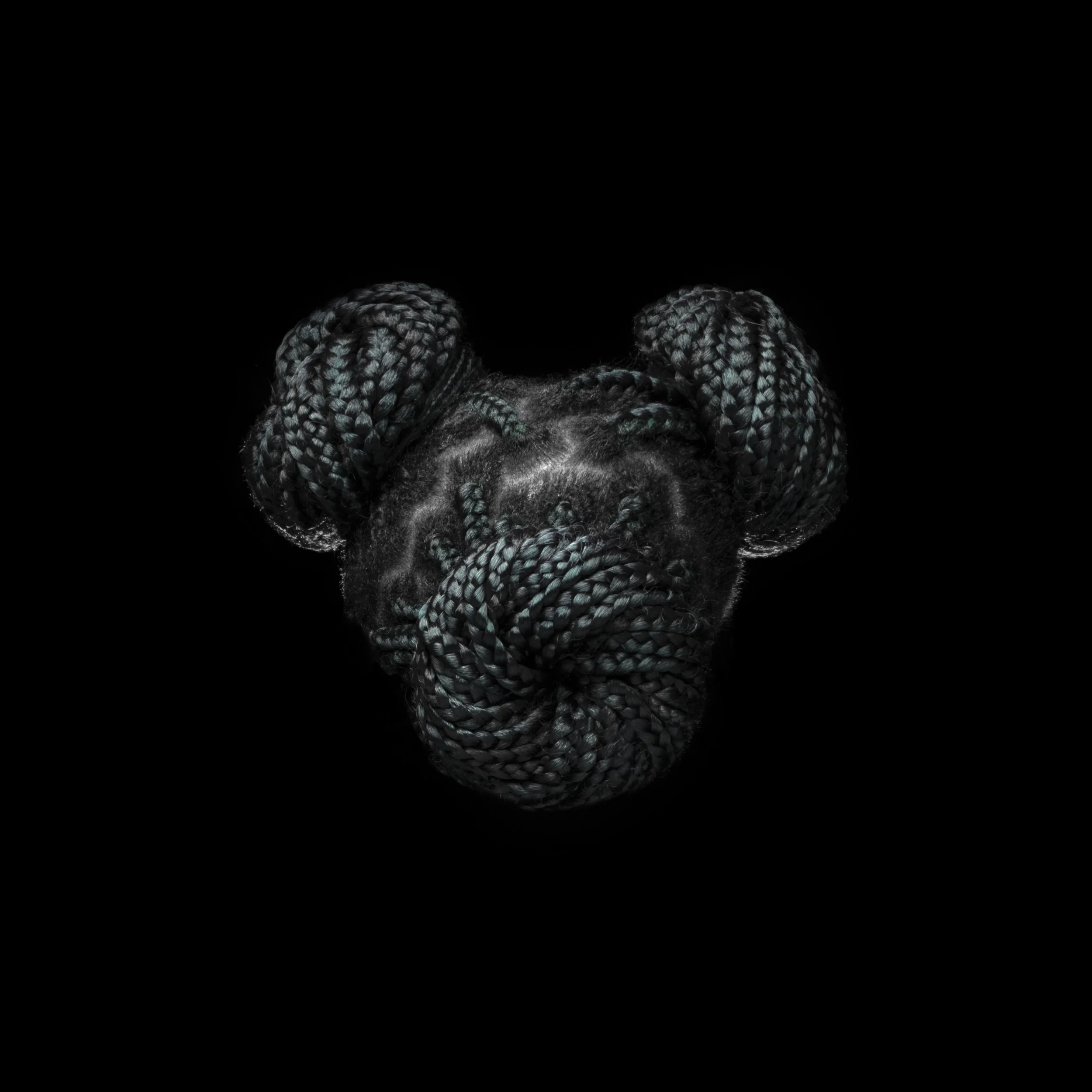 A black woman with thick braided hair styled in two buns, wearing a headscarf, against a black background.