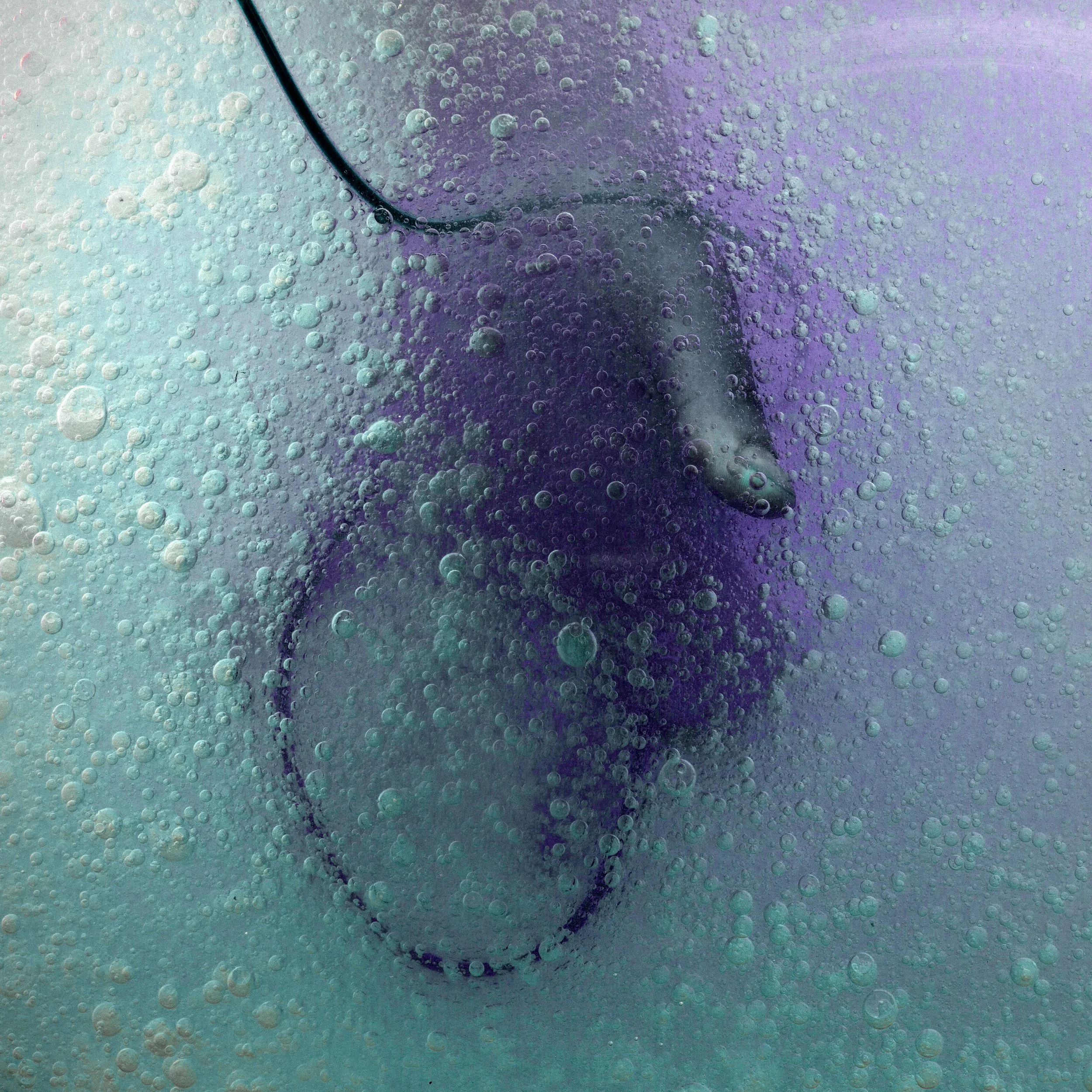 A computer mouse submerged in a bubbly purple and blue liquid.