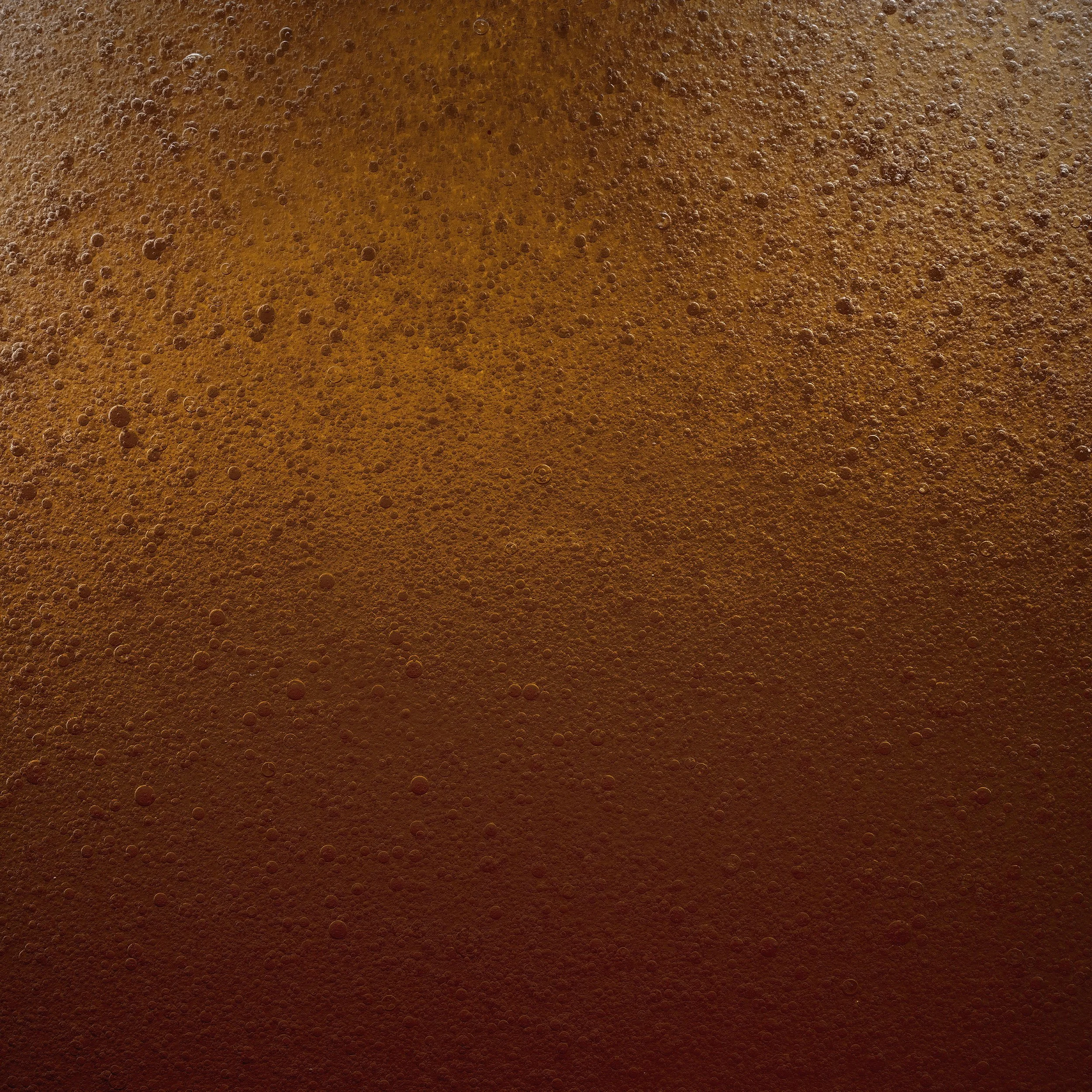 Close-up of a foamy, bubbly dark brown liquid, likely beer.