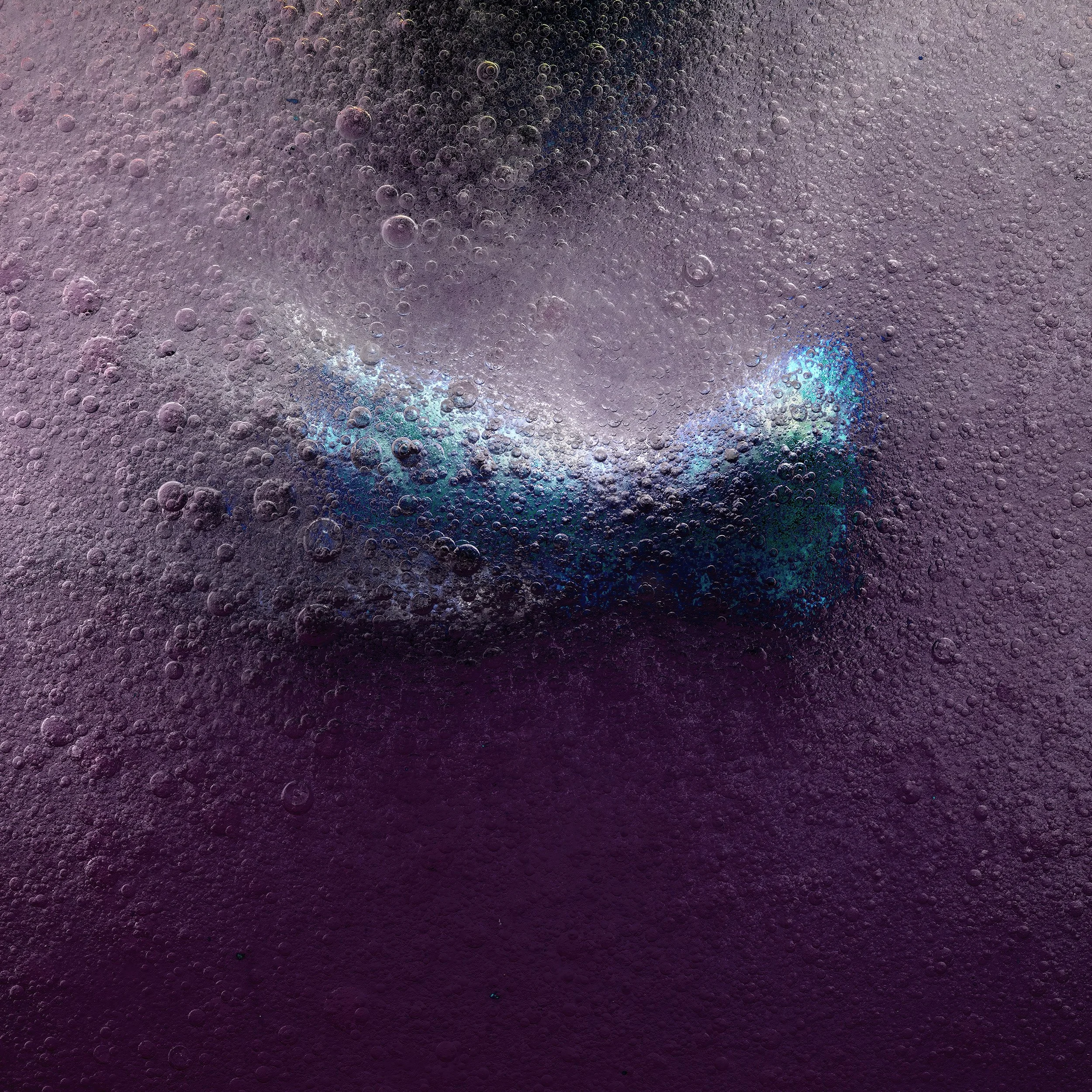 Close-up of a colorful, iridescent bubble with a dark, textured background filled with smaller bubbles.