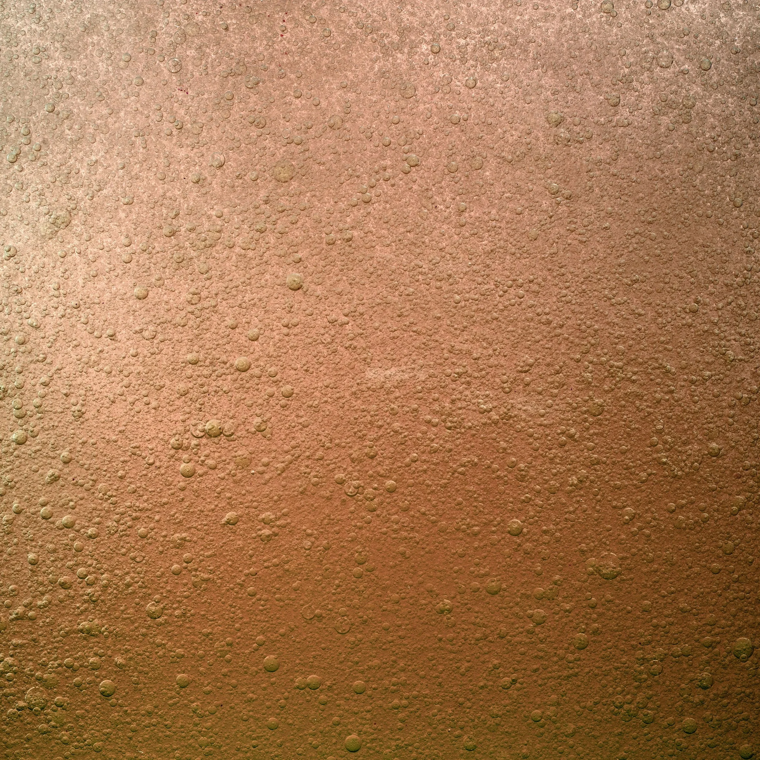 Close-up of a bubbly, fizzy surface with a gradient from pinkish to golden in color.