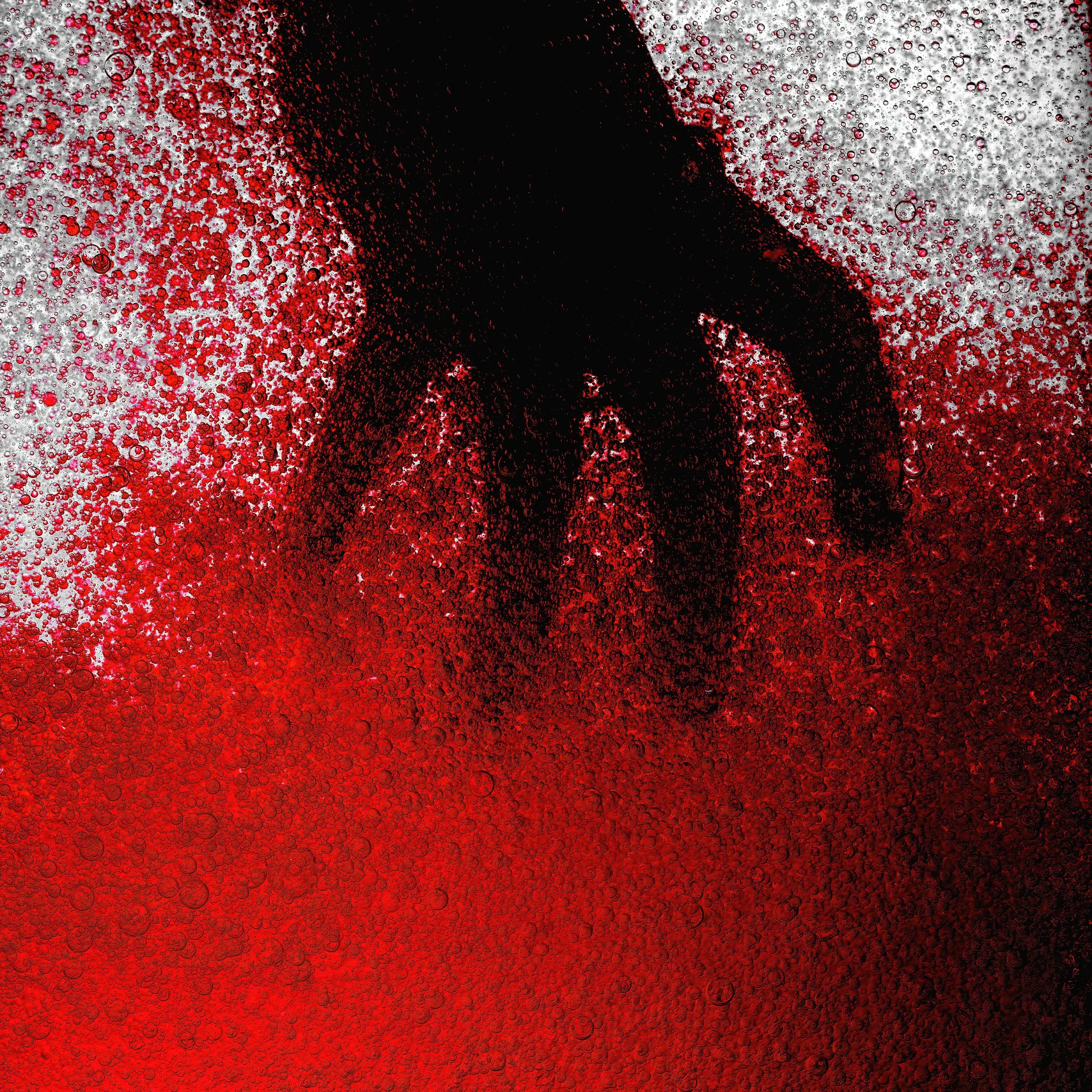 A silhouette of a person doing a handstand or yoga pose behind a glass of fizzy red beverage with bubbles.